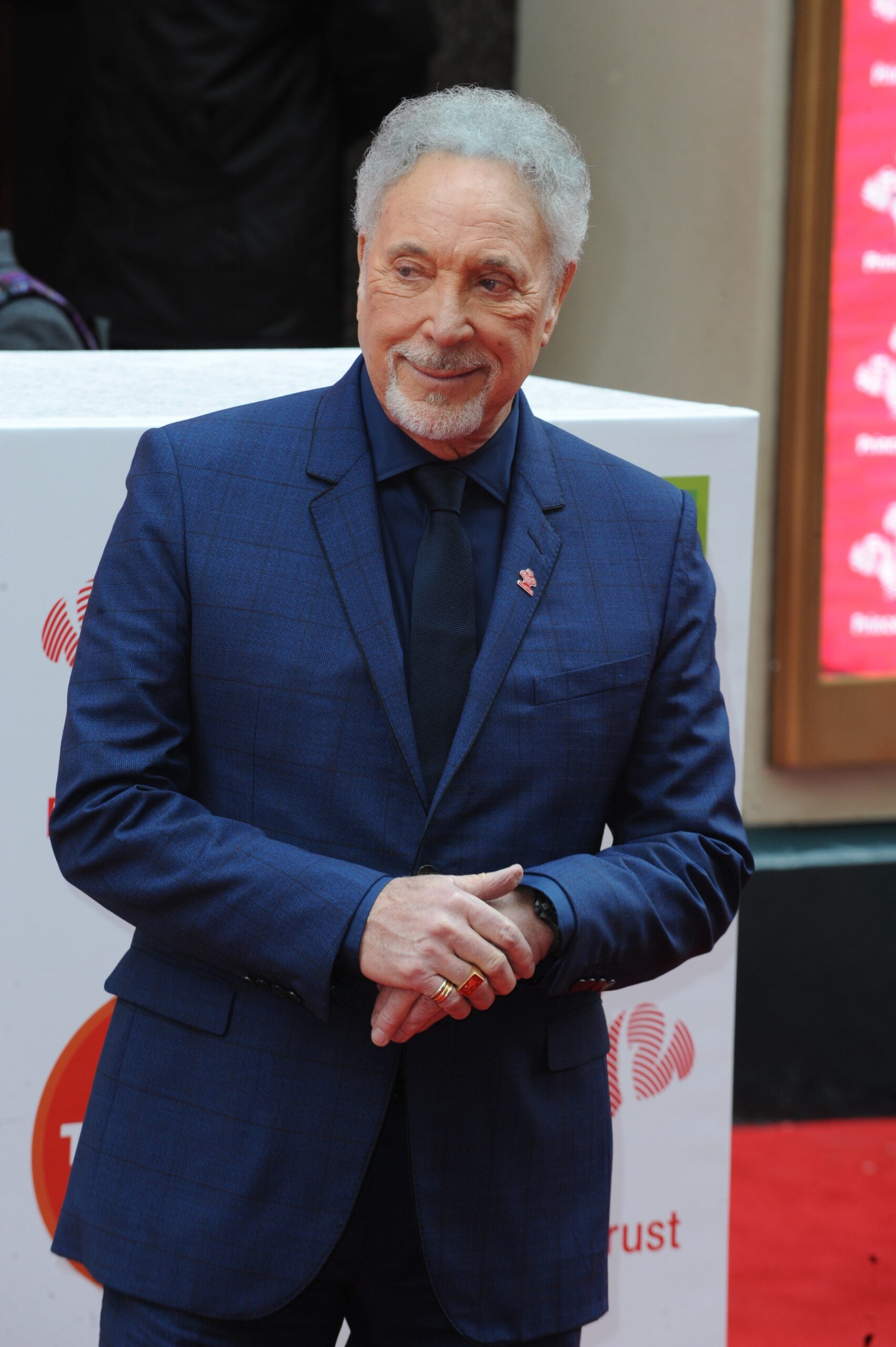 Tom Jones smiling slightly in a blue suit