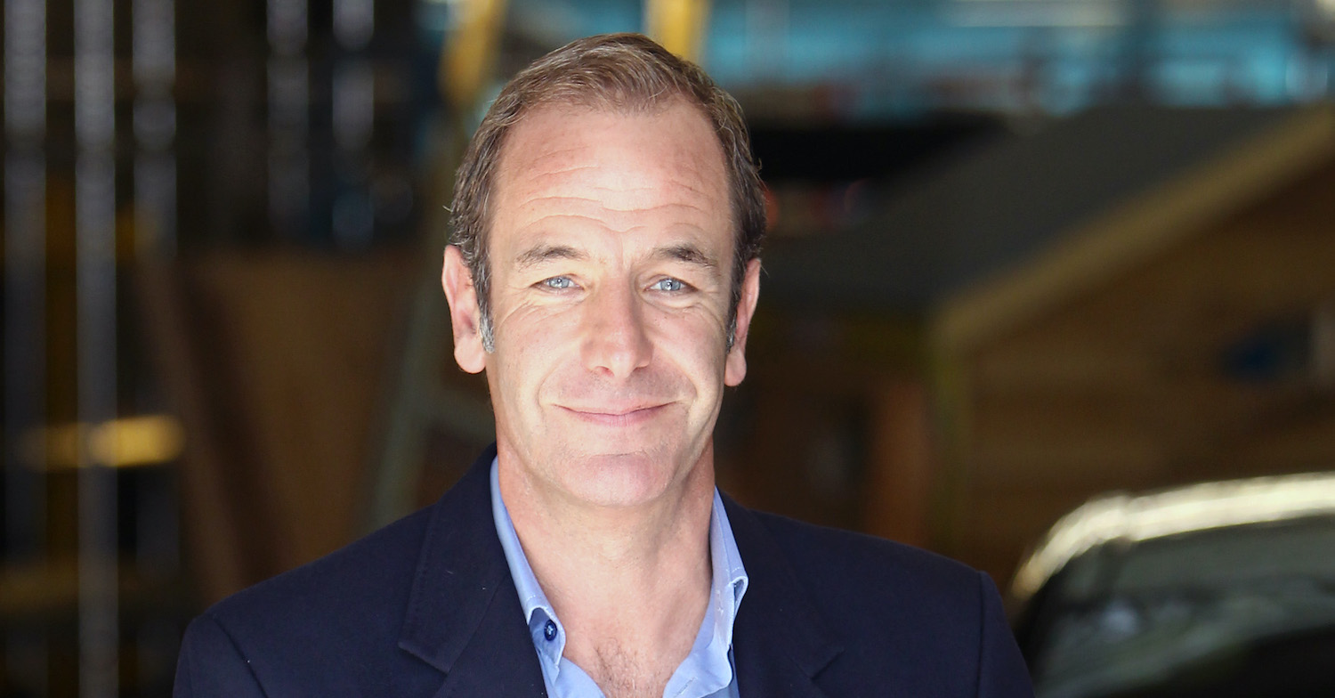 Robson Green smiling as he poses in a smart navy jacket