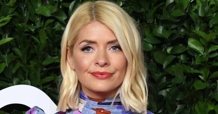 Holly Willoughby smiles on red carpet wearing a floral dress