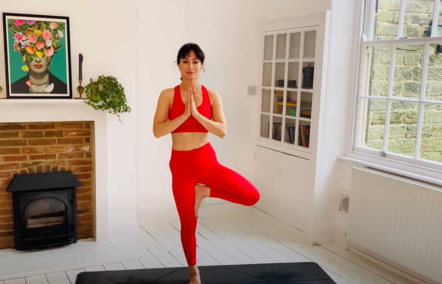 Dressed in red Roxy Shahidi performs a yoga pose