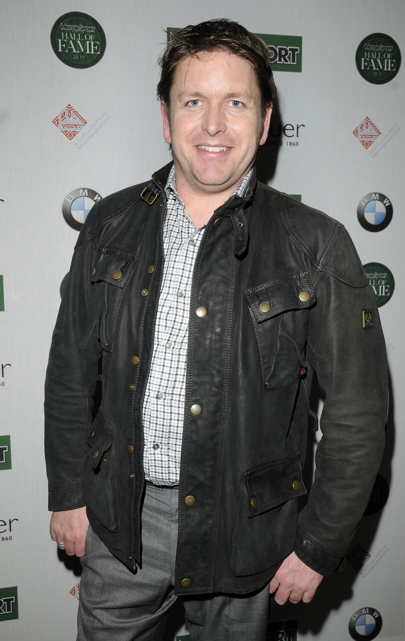James Martin smiles to camera dressed in a wax jacket at a press event