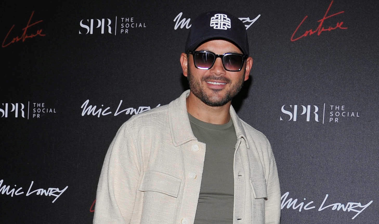 Ryan Thomas on the red carpet in cap and sunglasses
