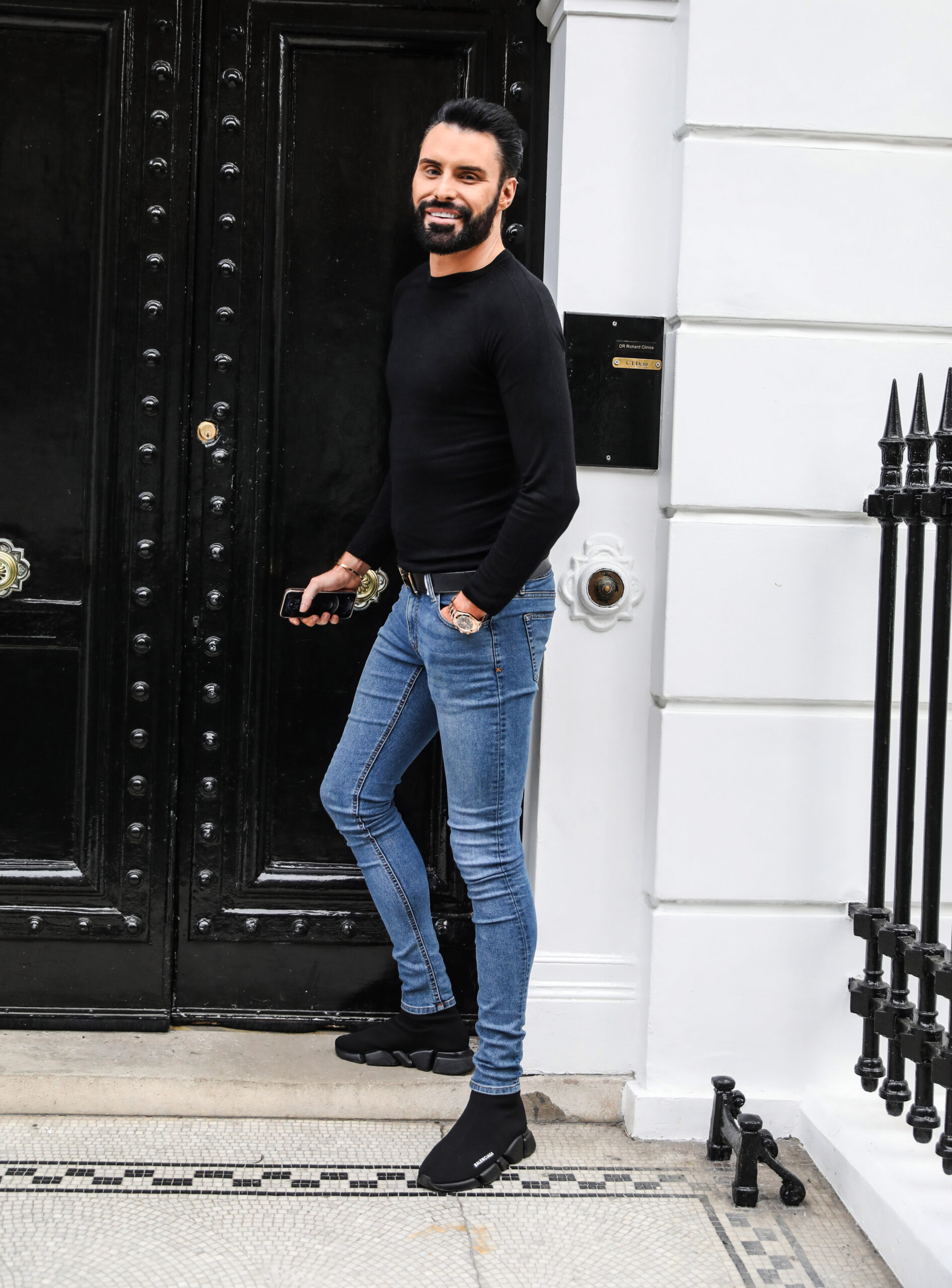 Rylan Clark standing by a black door