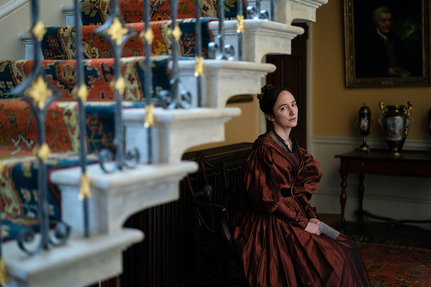 Gentleman Jack's Mariana Lawton tilts her head towards the camera posing beneath stairs
