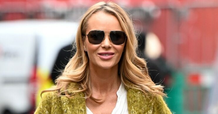 Amanda Holden smiling in yellow coat and sunglasses