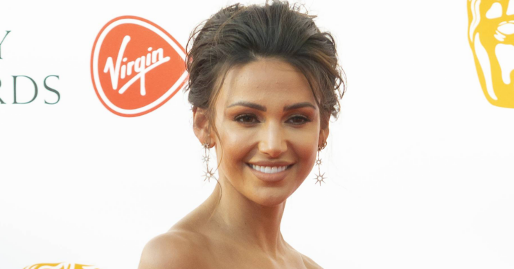Michelle Keegan smiling in a strapless dress