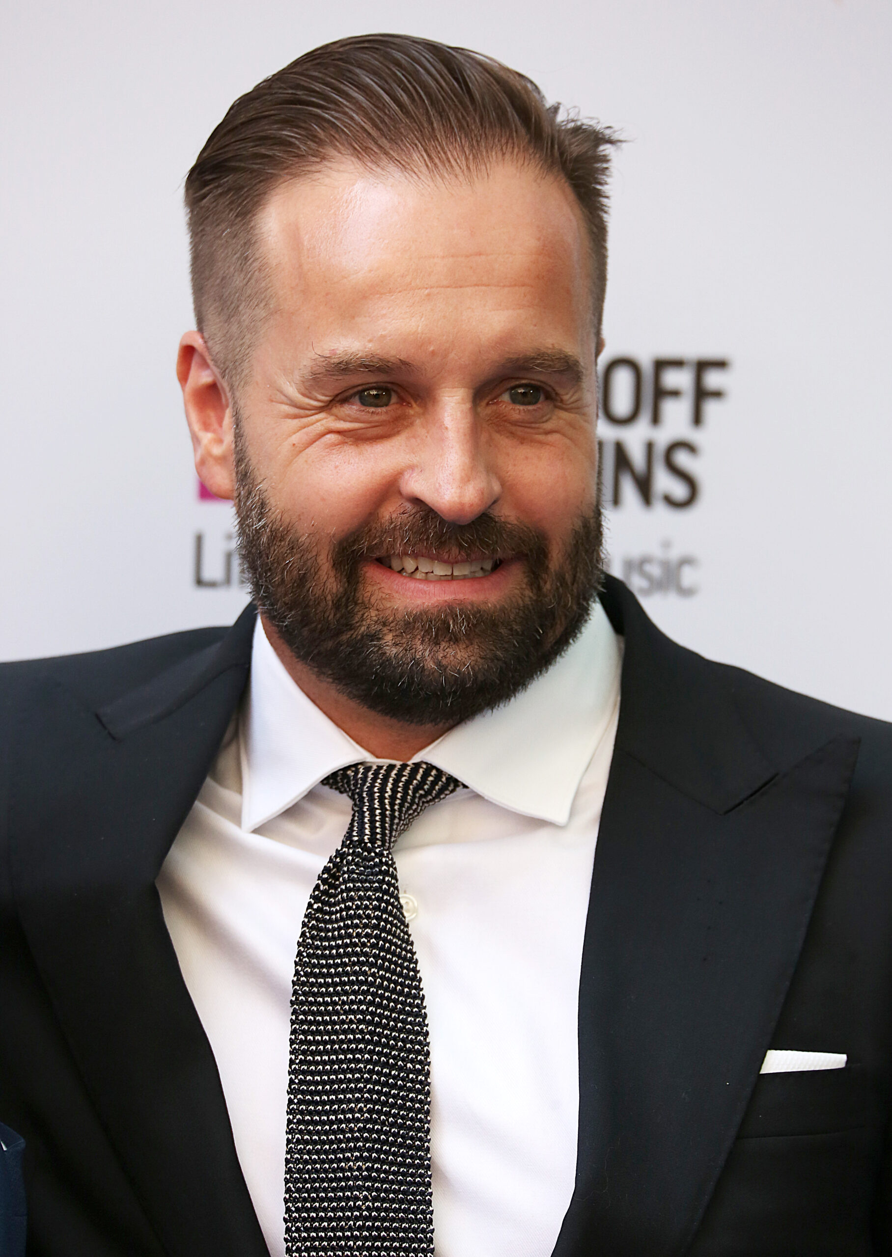 Alfie Boe smiling against a white backdrop