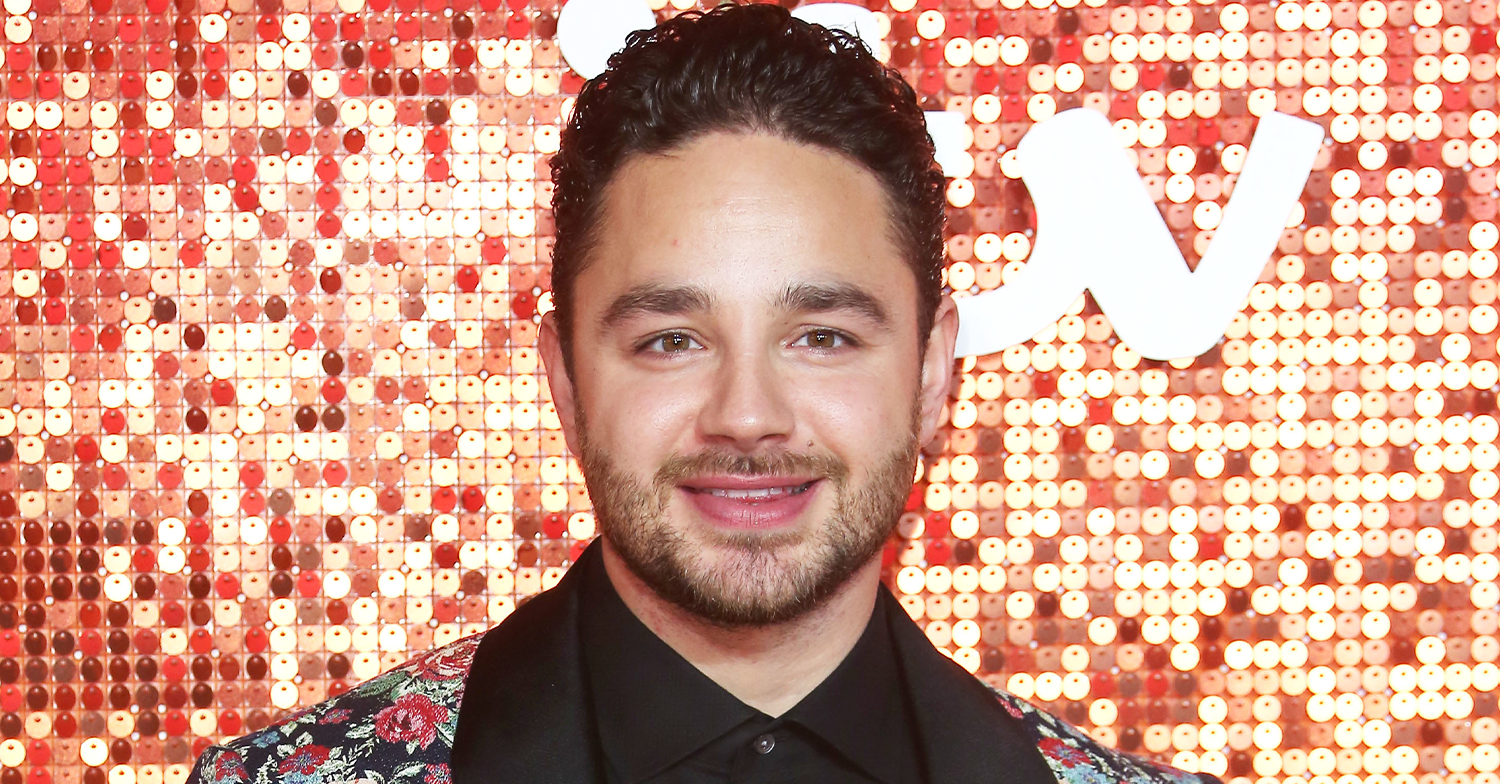 Adam Thomas standing against a glittery background