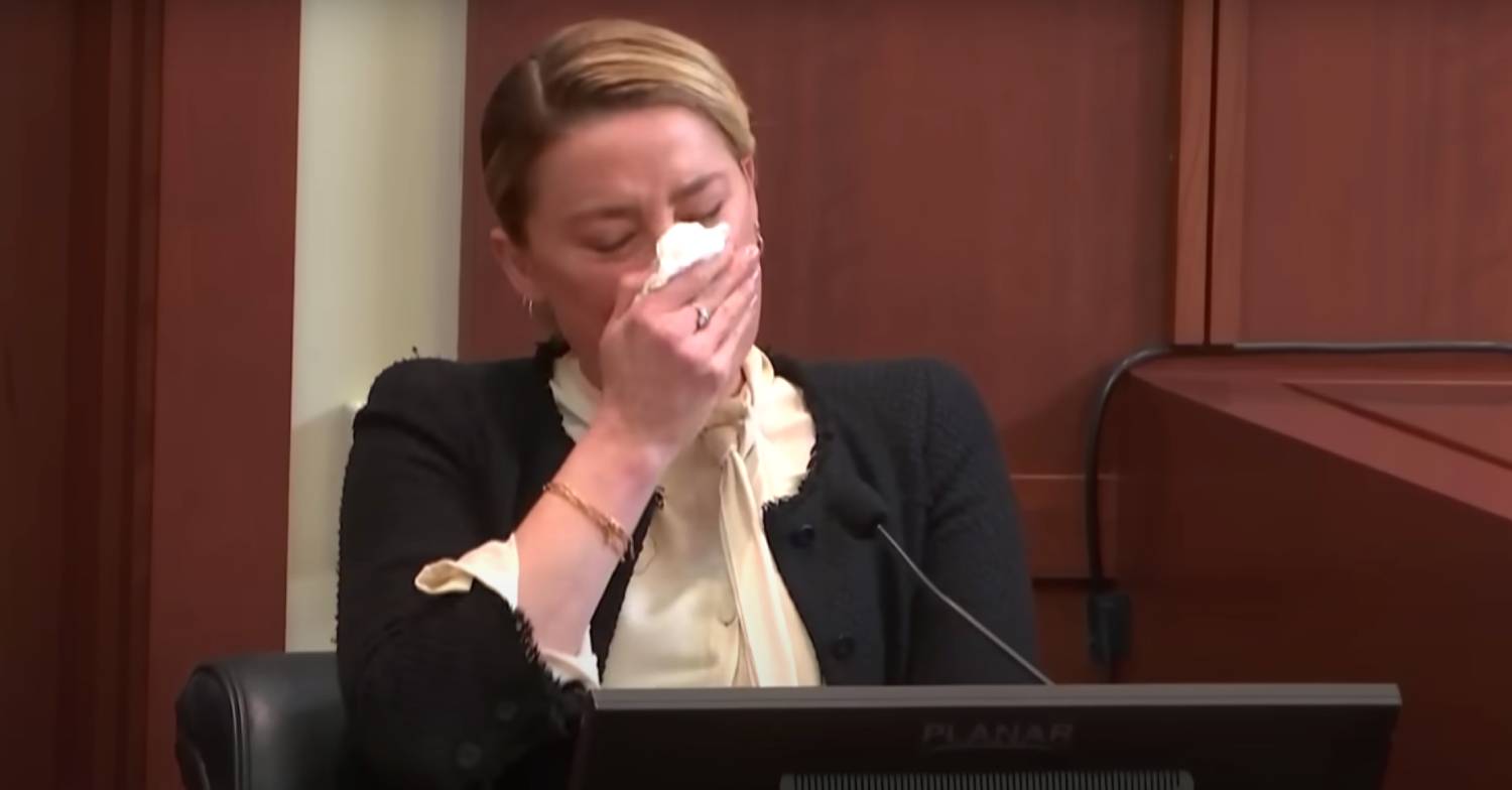 Amber Heard holds a handkerchief to her face