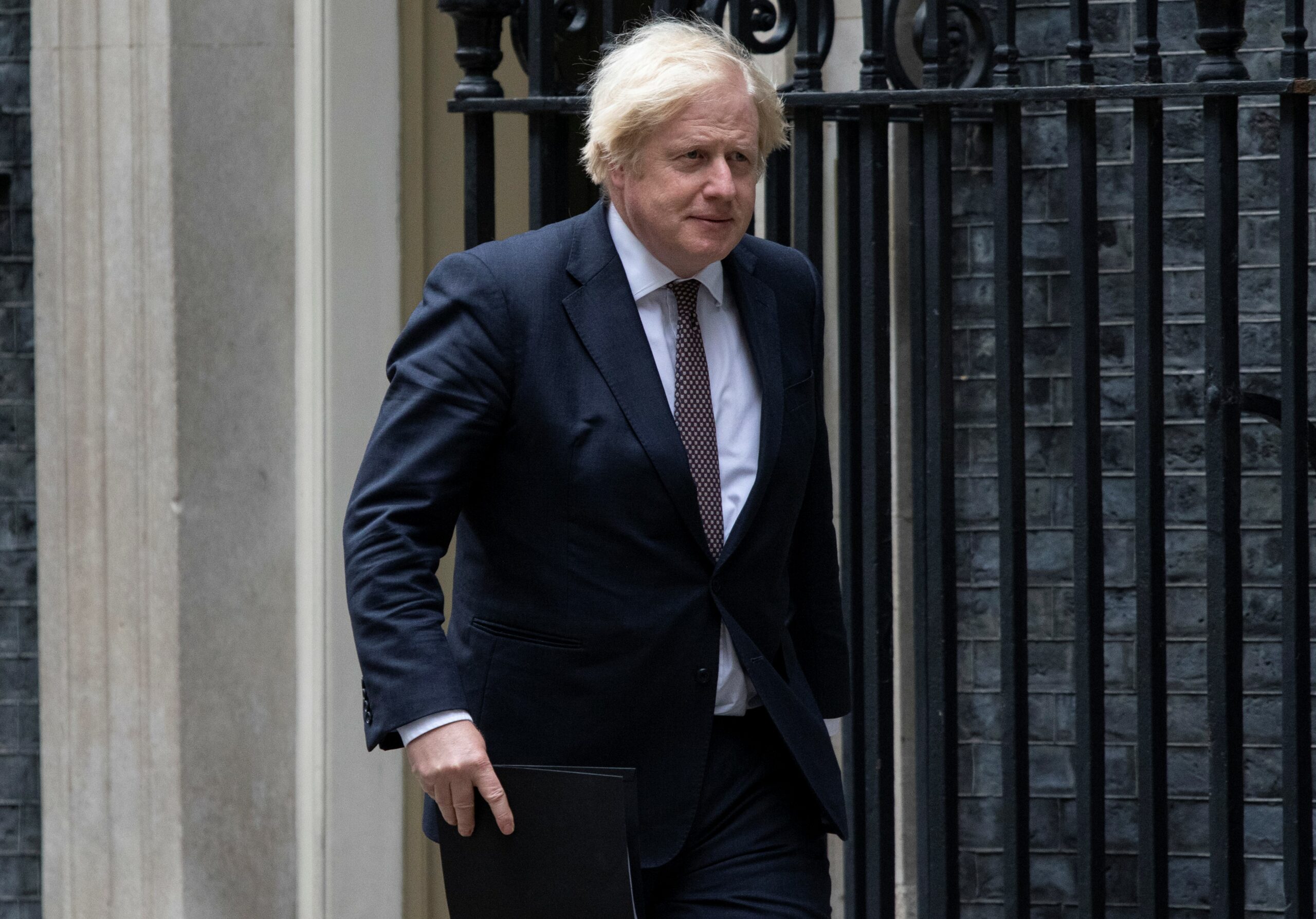 Boris Johnson walking outside Downing Street while carrying a folder
