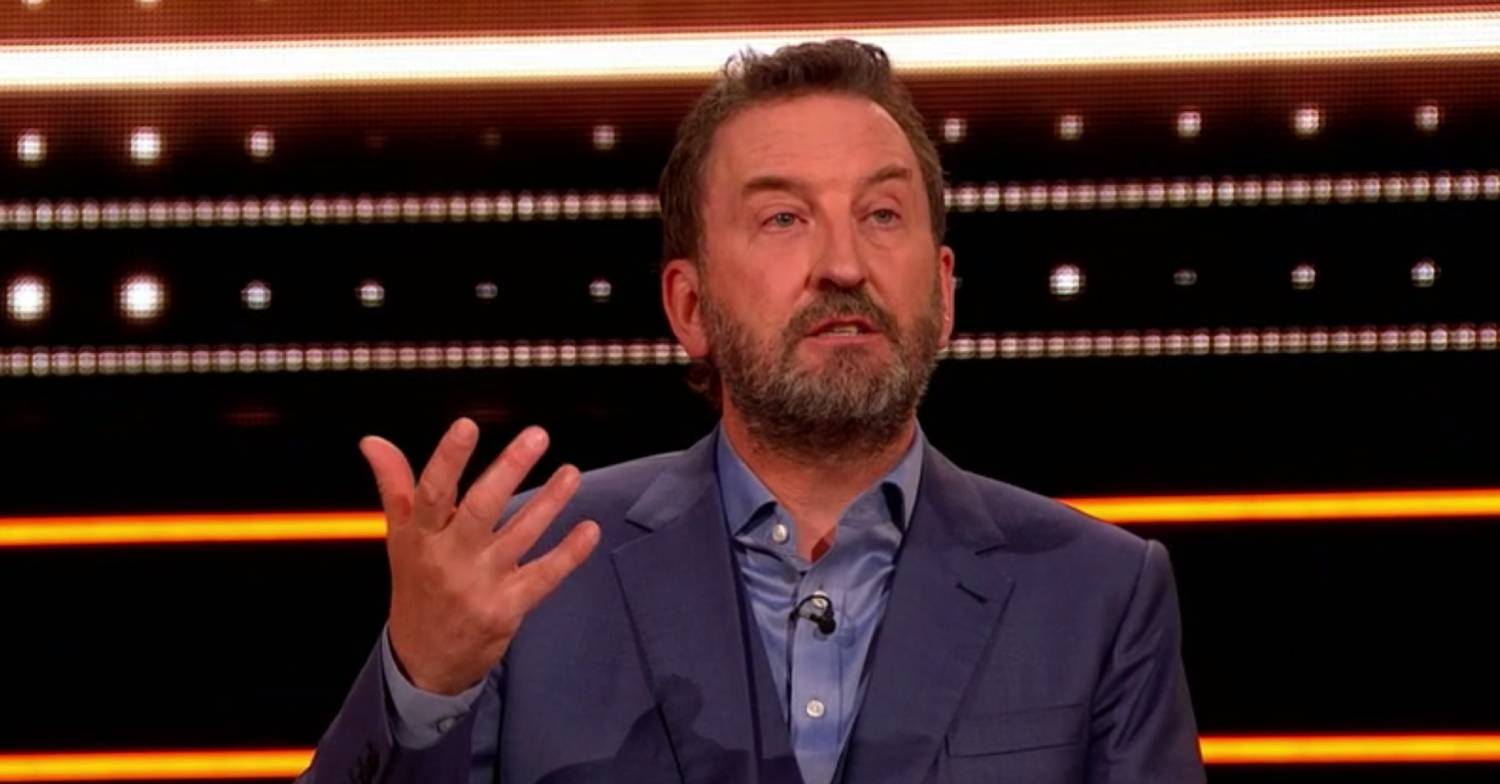 Lee Mack raises his hand while hosting The 1% Club