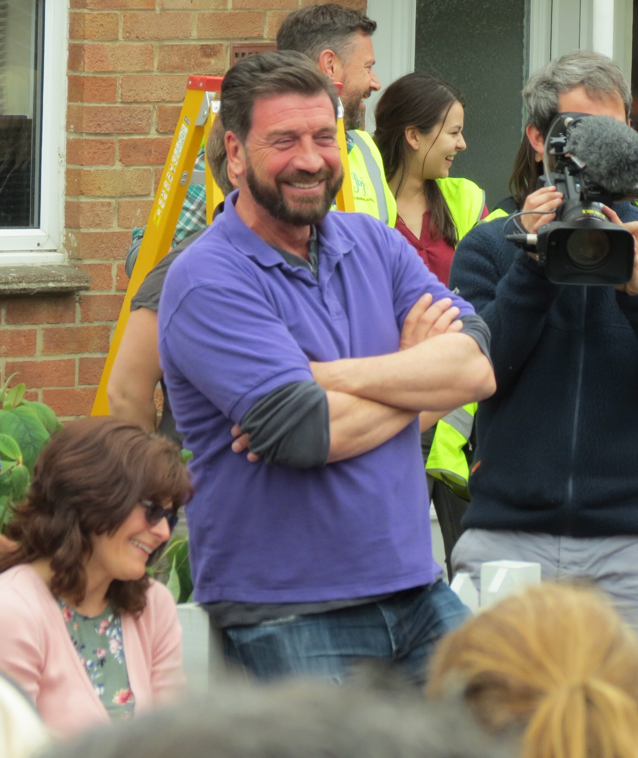Nick Knowles grinning outside a house on DIY SOS