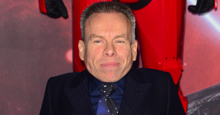 Warwick Davis smiling on the red carpet
