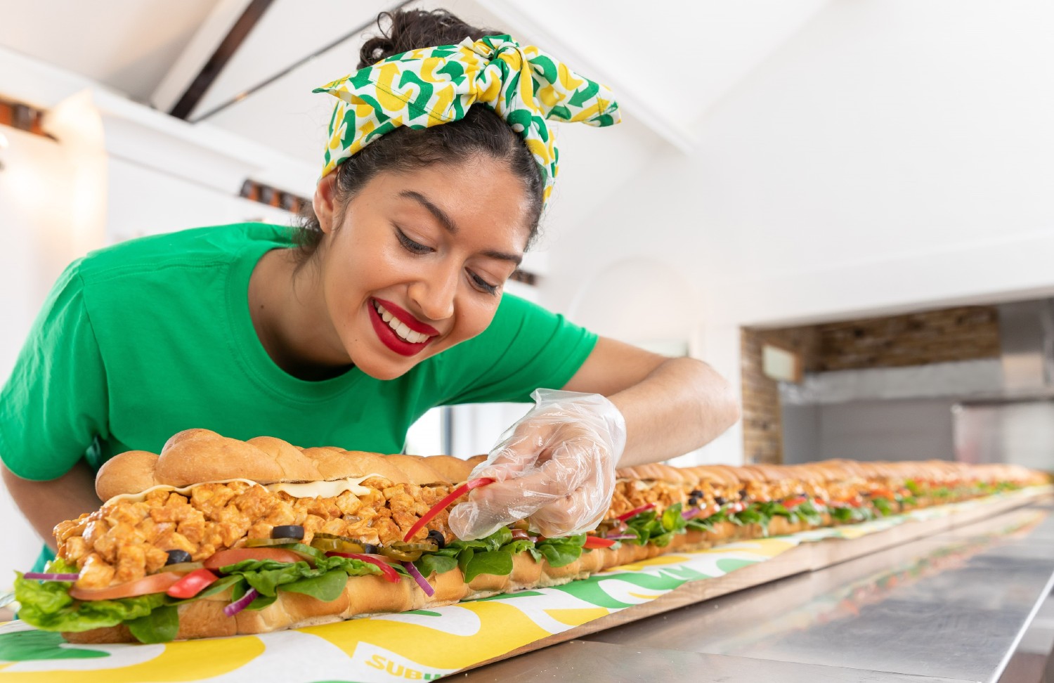 Subway worker smiling as she makes a seven-meter sub