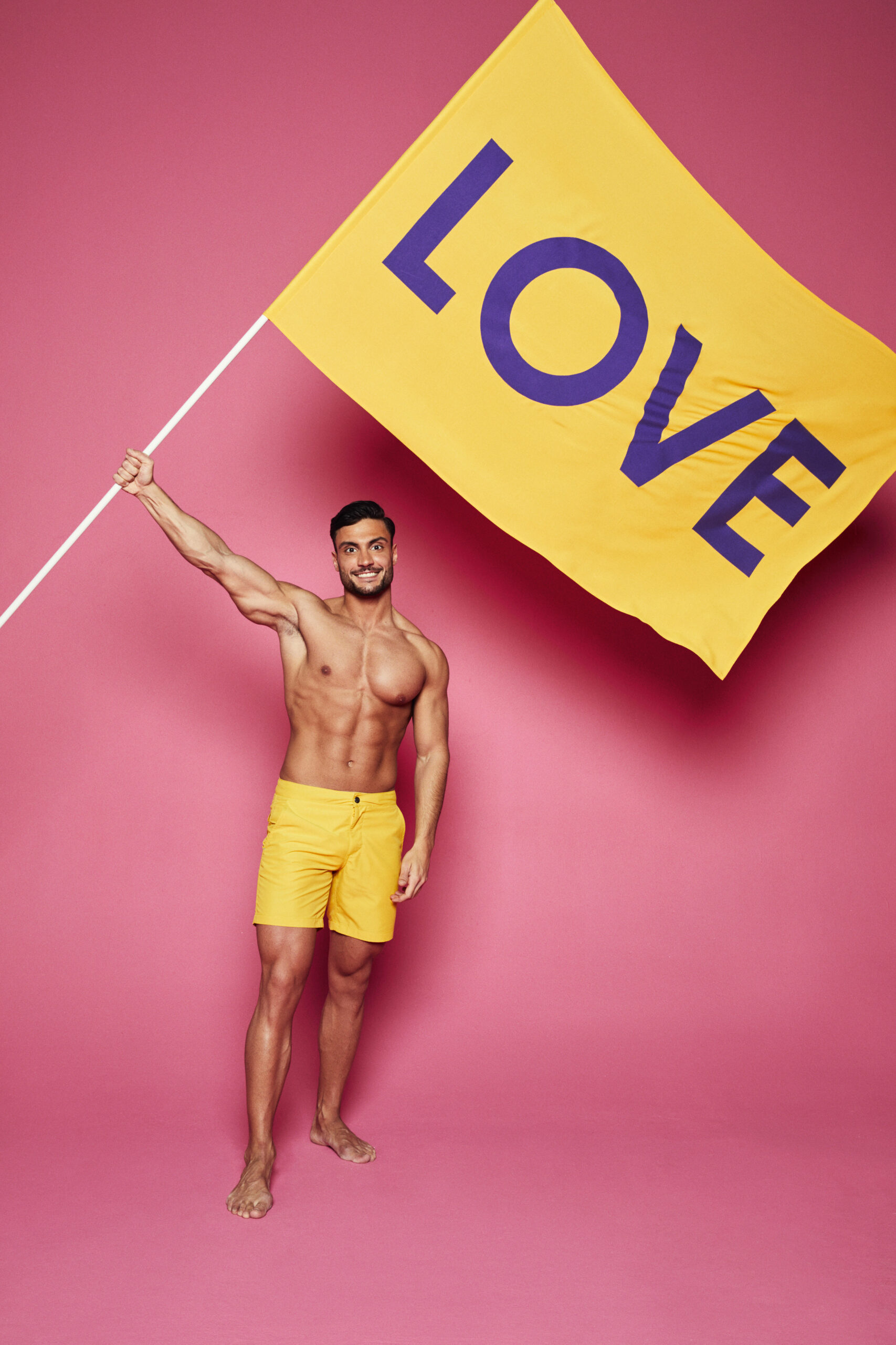 Love Island contestant Davide in swimwear holding a flag