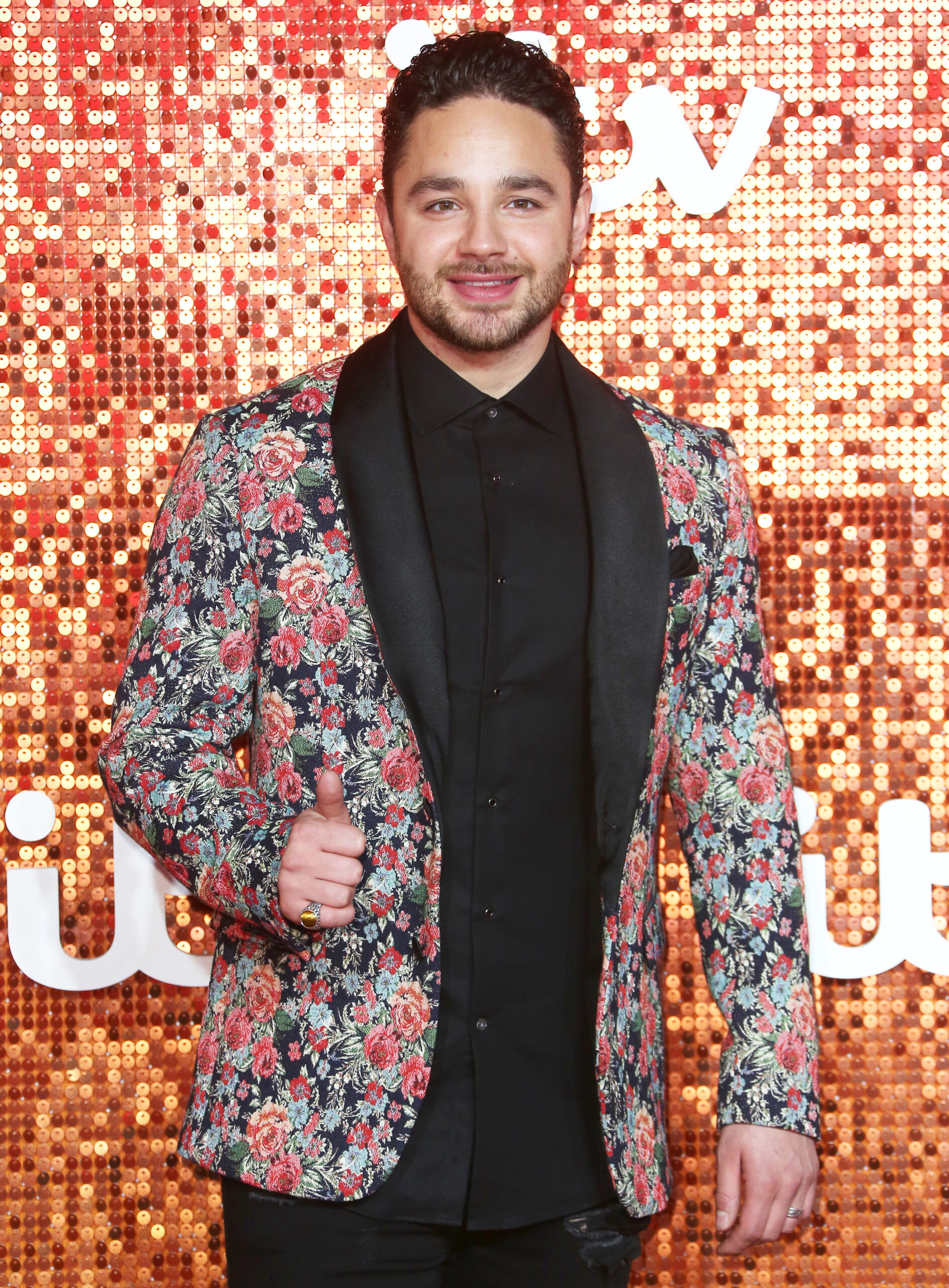 Adam Thomas standing against a glittery background