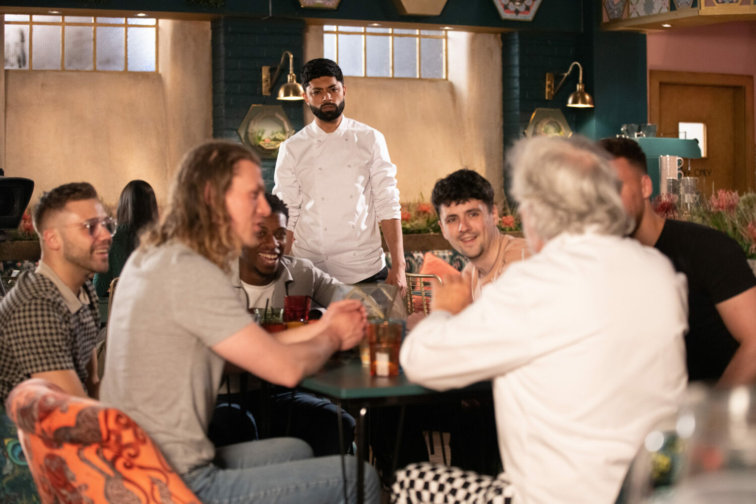 Zeedan looking worries as he watches Stu with a group of guys Coronation Street