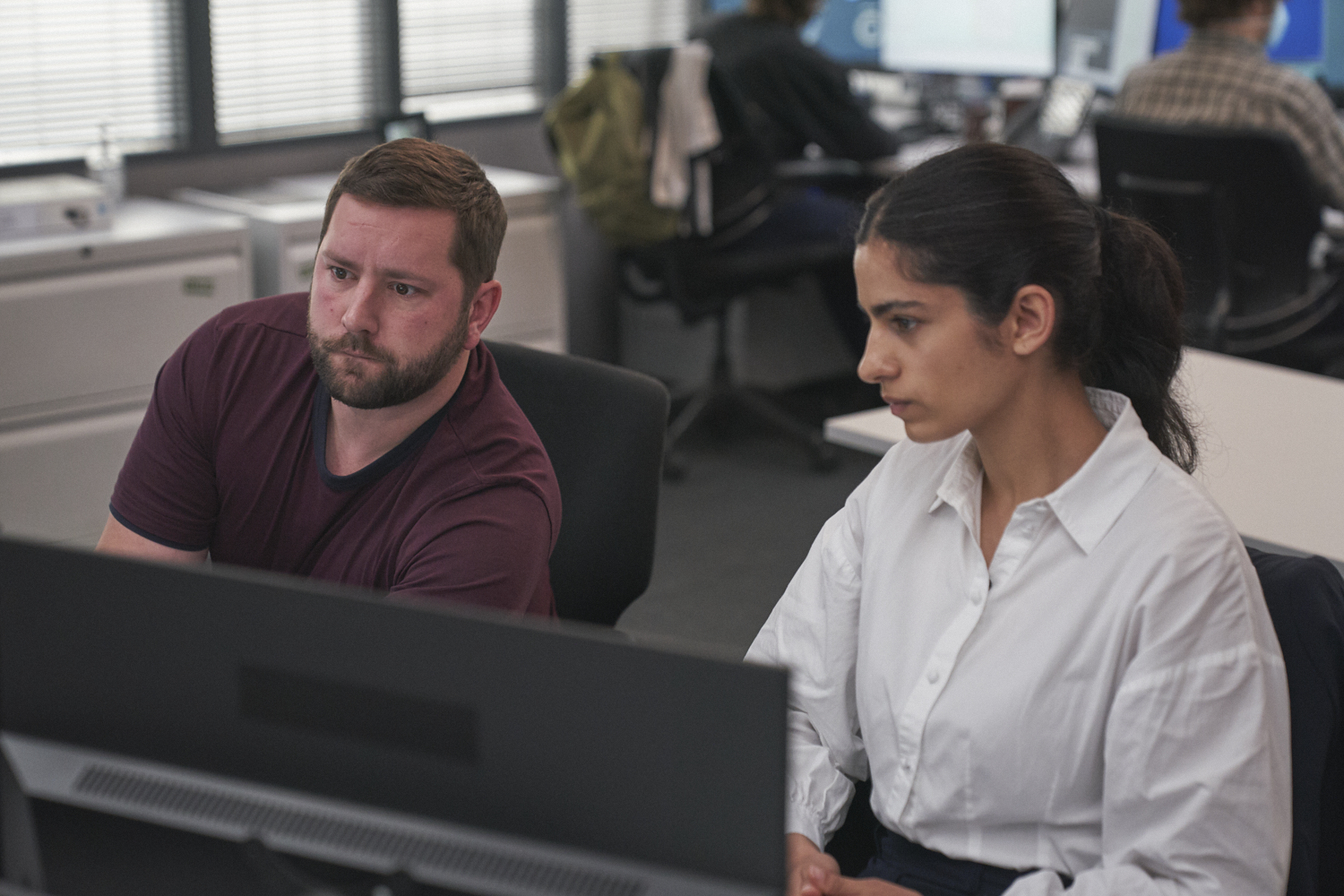 Hannah Khalique-Brown as Saara and Joss Porter as Phil staring at a computer screen in Undeclared War (Credit: Channel 4)