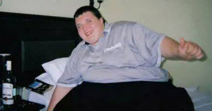 Britain's Fattest Man smiling sitting on a bed