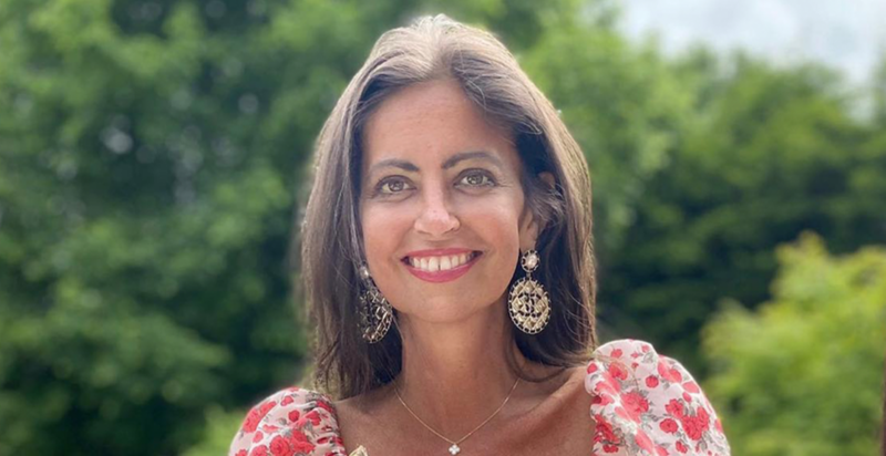 Deborah James smiling wearing red floral