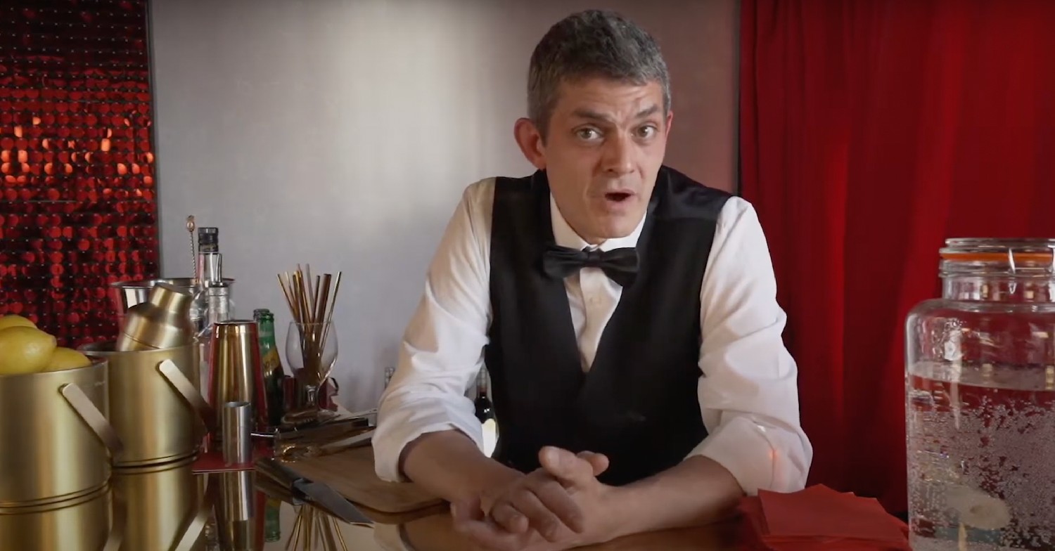 Merlin Griffiths, dressed in a waistcoat and bow tie, speaking to camera 