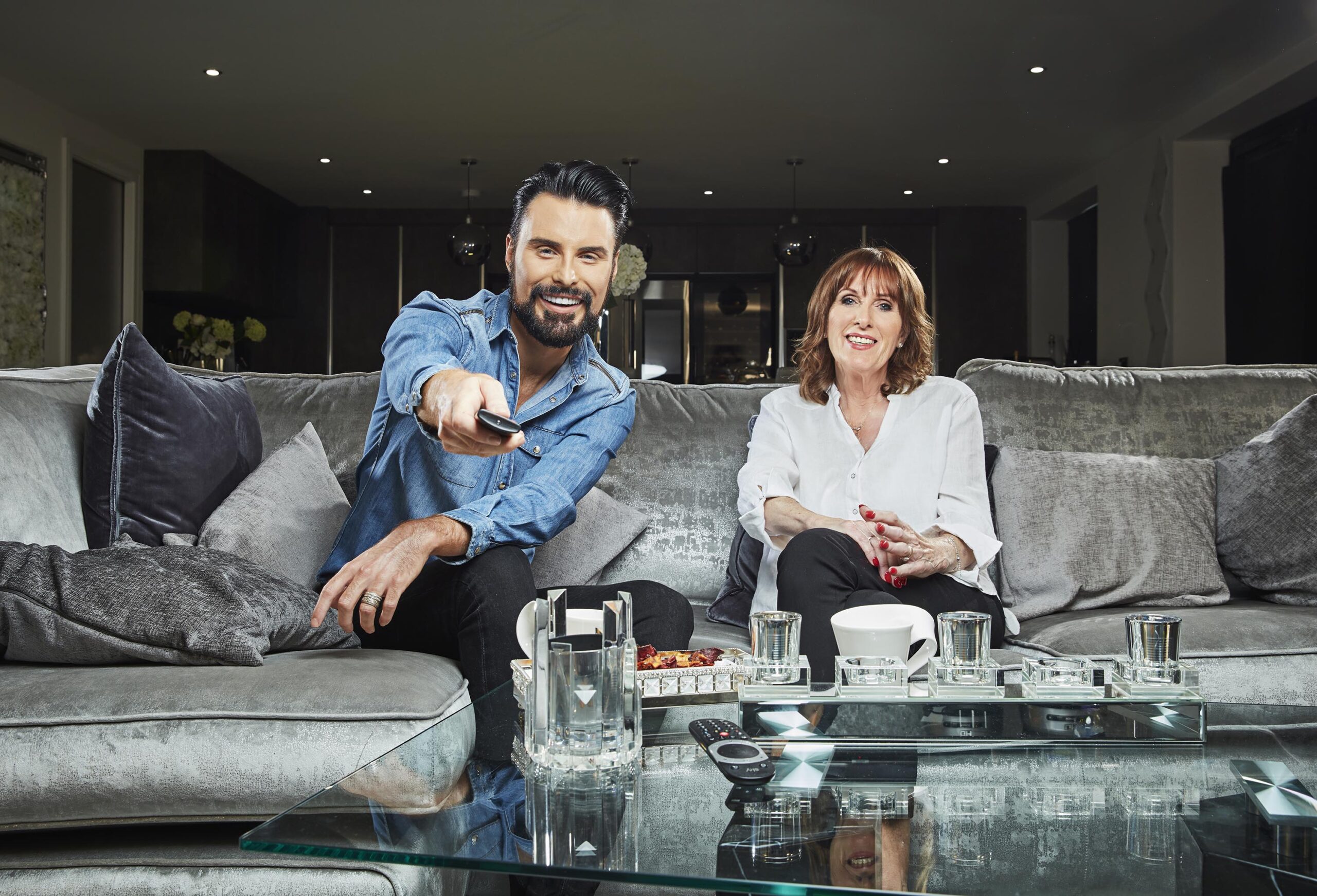 Rylan points the remote at the telly as his mum smiles on the sofa on Celebrity Gogglebox