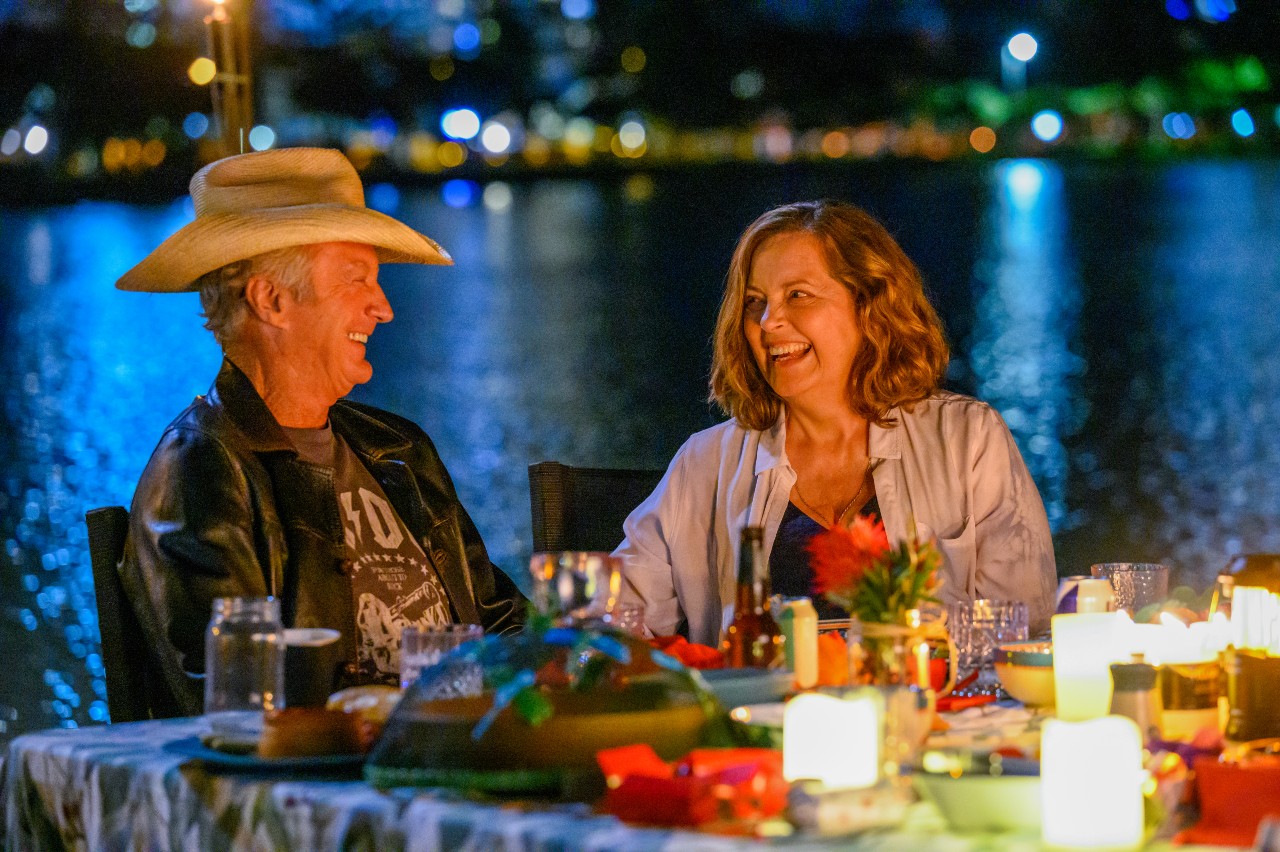 Darby and Joan smiling over drinks and dinner at night