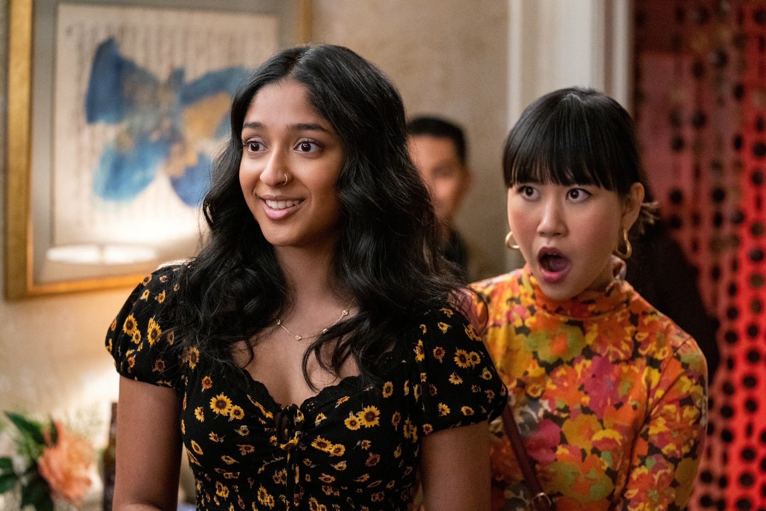 Devi in Never Have I Ever smiles as friend gasps behind her at party