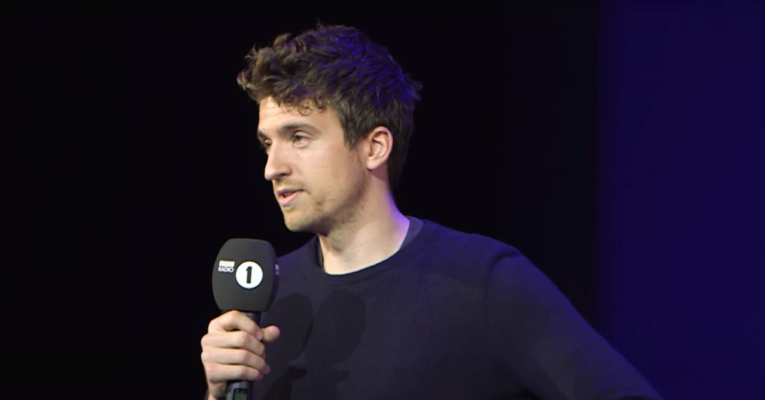 Greg James speaks into a microphone