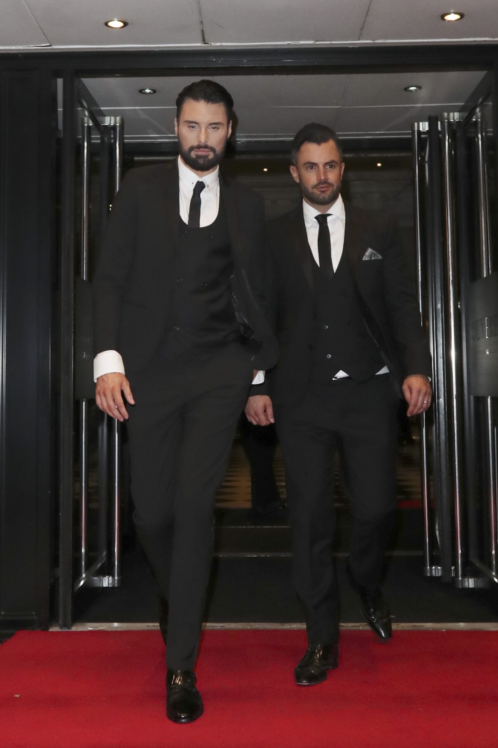 Rylan Clark walks hand in hand with Dan Neal as they wear suits