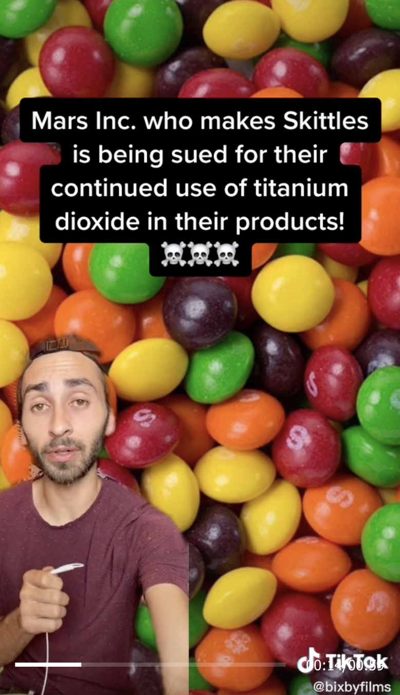 Man sitting in front of a picture of skittles