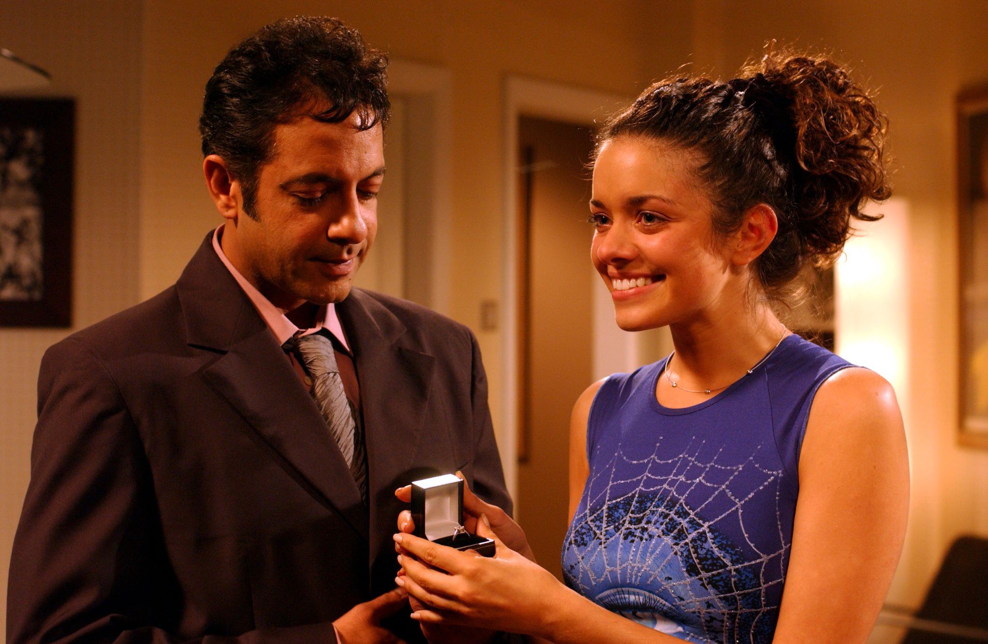Dev looks at teh ring as Geena smiles in Corrie