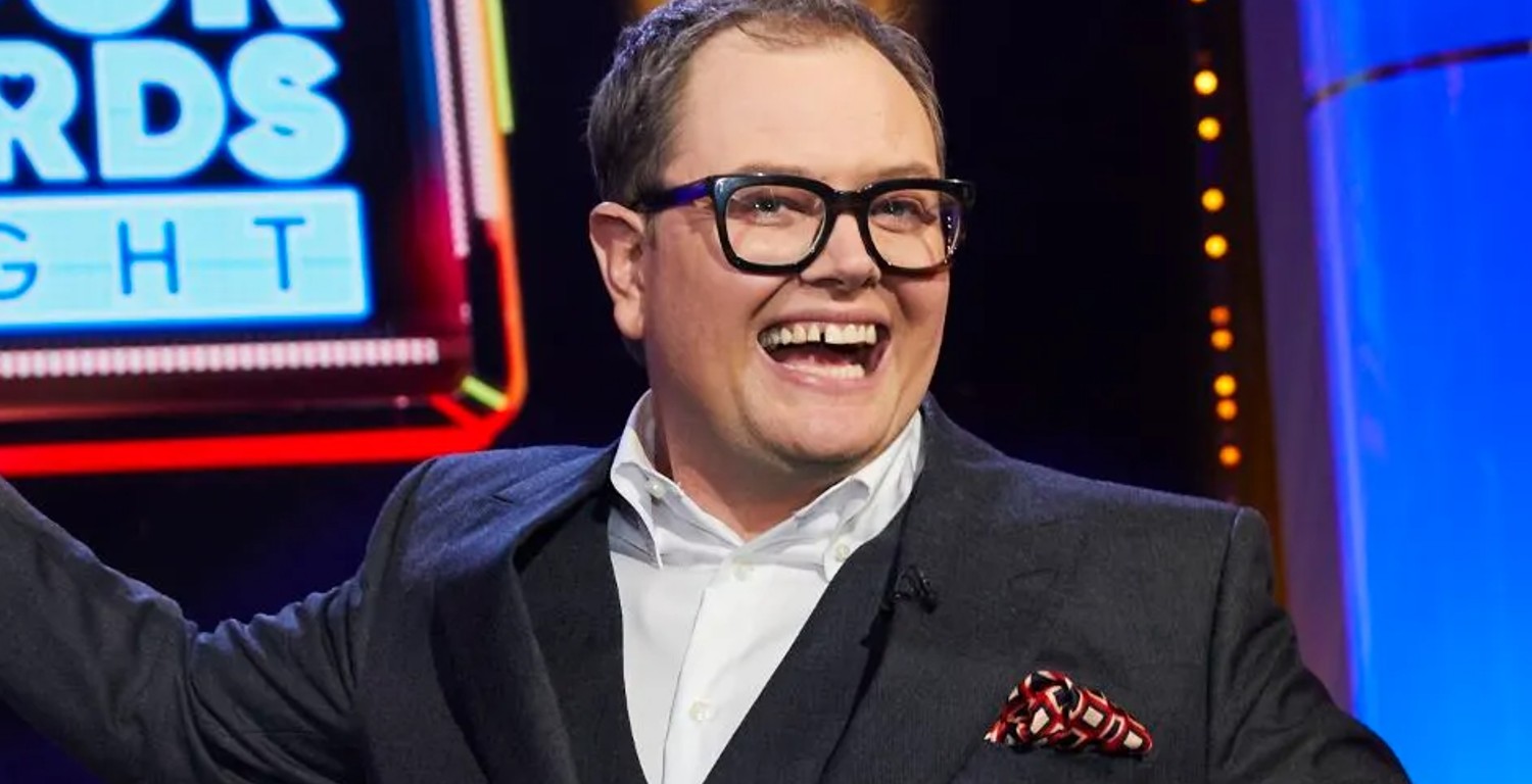 Alan Carr smiling on his ITV gameshow and wearing a suit