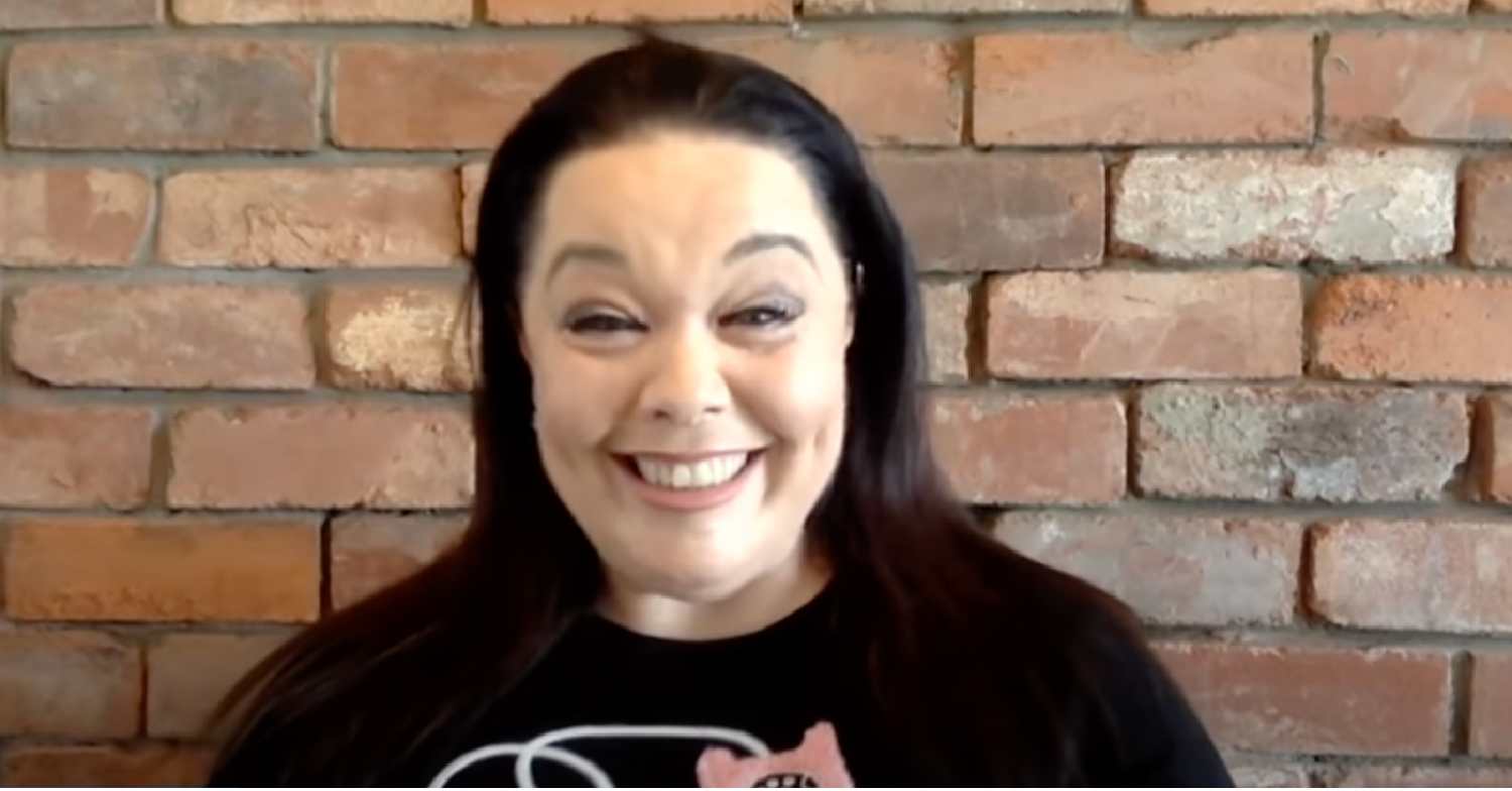 Lisa Riley standing in front of a brick wall smiling