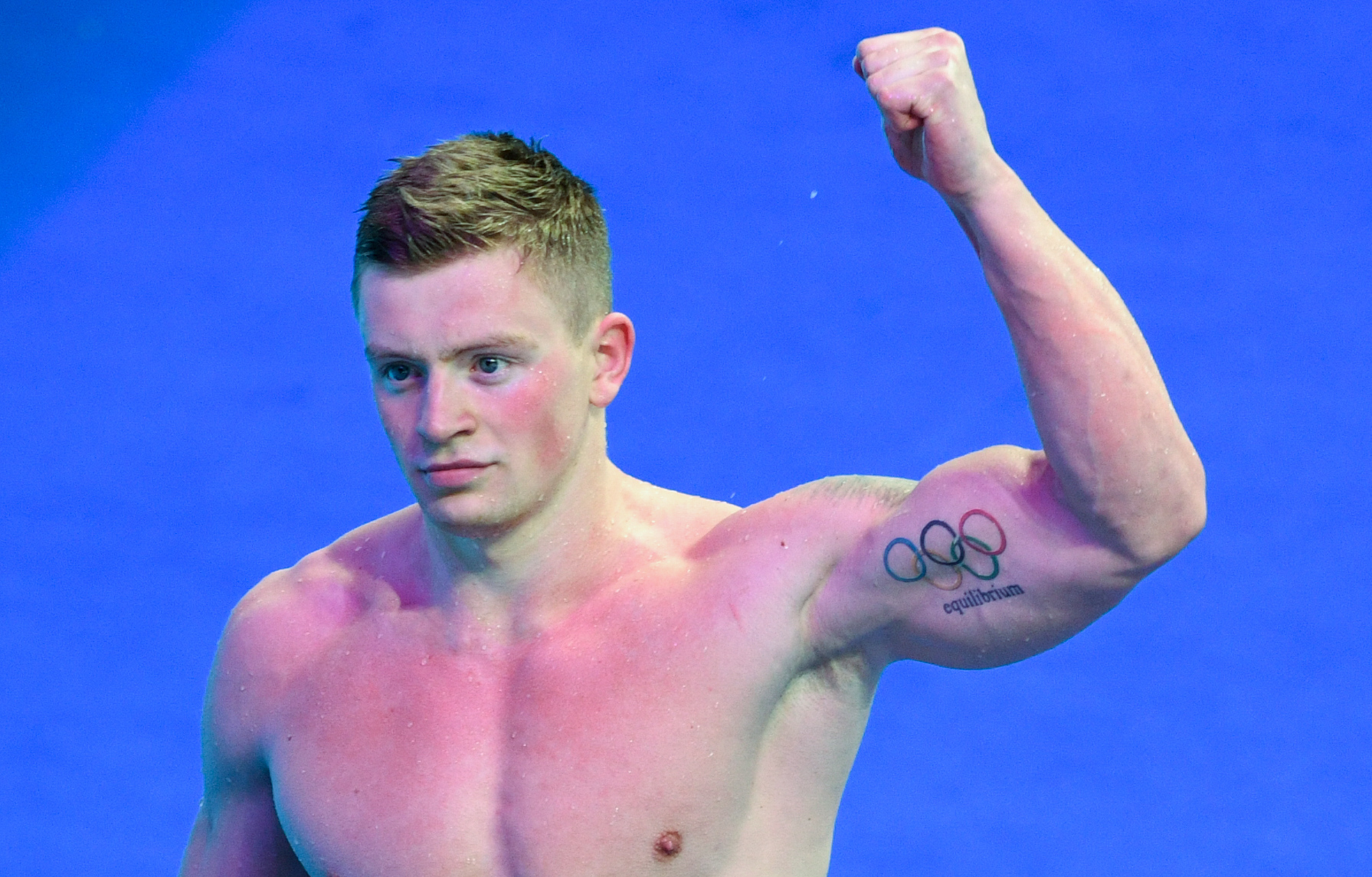 Adam Peaty with arm in air showing olympic tattoo
