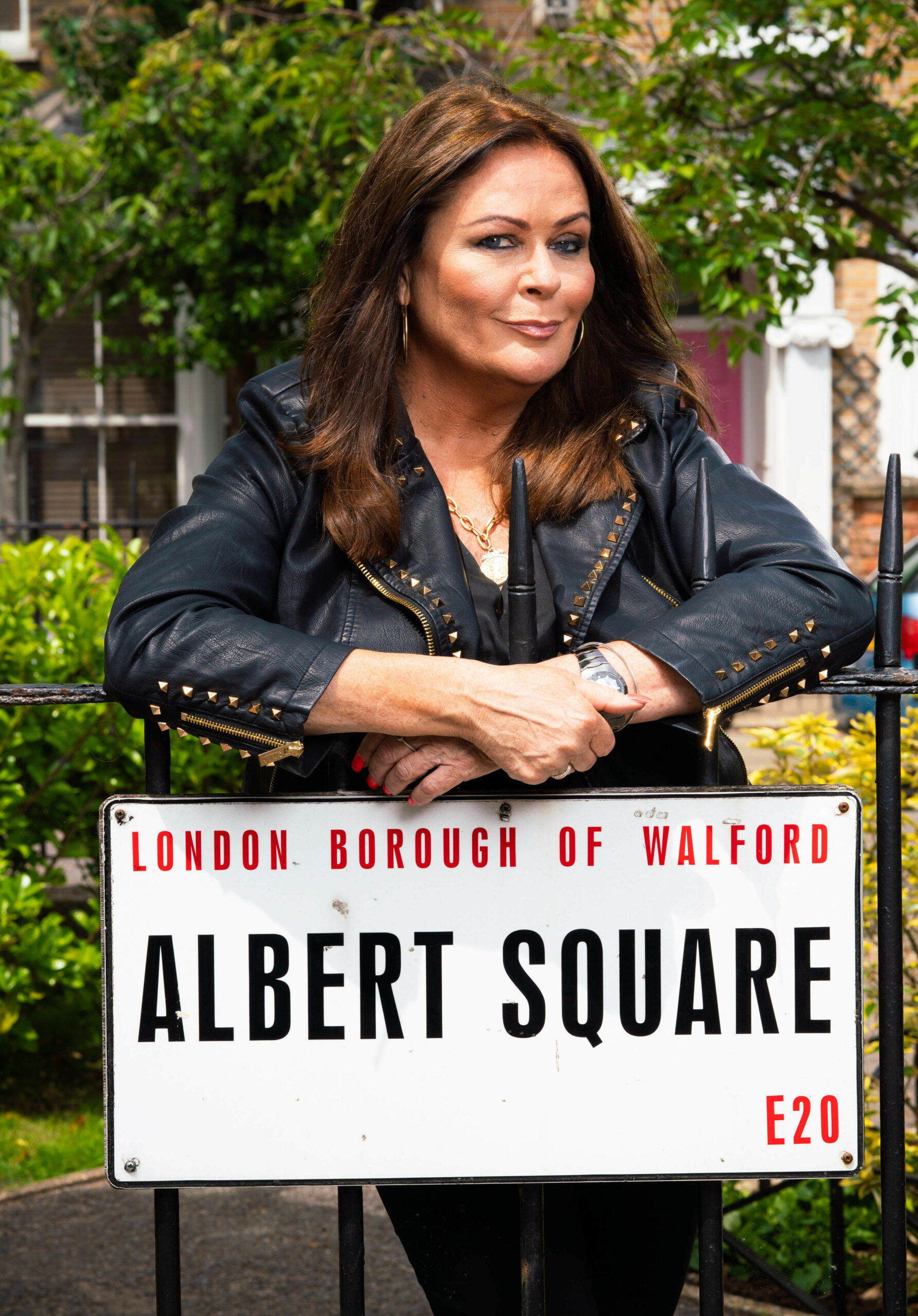Kate Robbins leaning on Albert Square sign for EastEnders