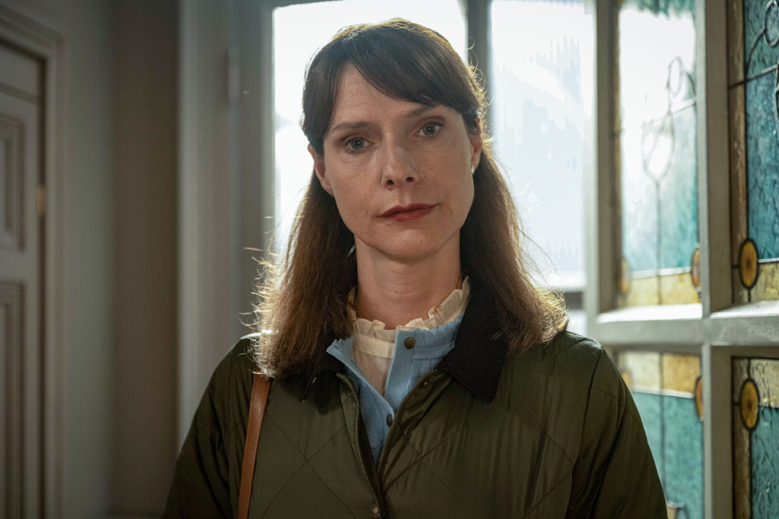Janice Fife as Dolly Wells in Inside Man, she looks into the camera with a neutral expression, she's in a house