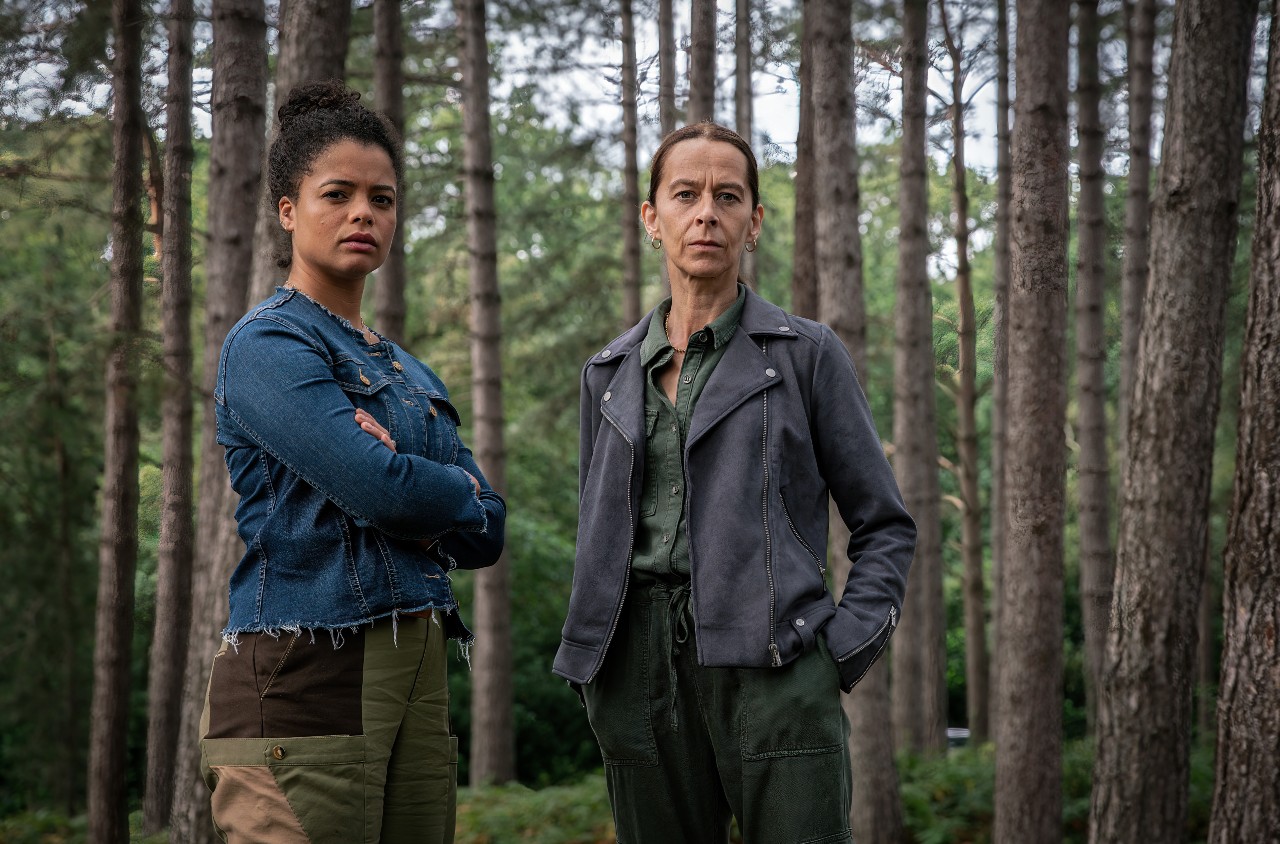 Lydia West as Beth Davenport (left) and Kate Dickie (right), they stand in a forest looking off to the right together