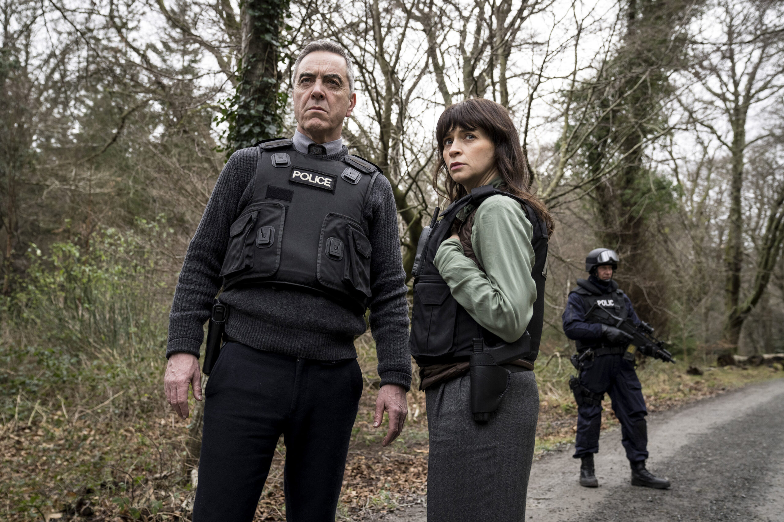 Bloodlands,First Look,Tom Brannick (JAMES NESBITT), Niamh McGovern (CHARLENE McKENNA), They are in woods, in police uniforms with worried expressions