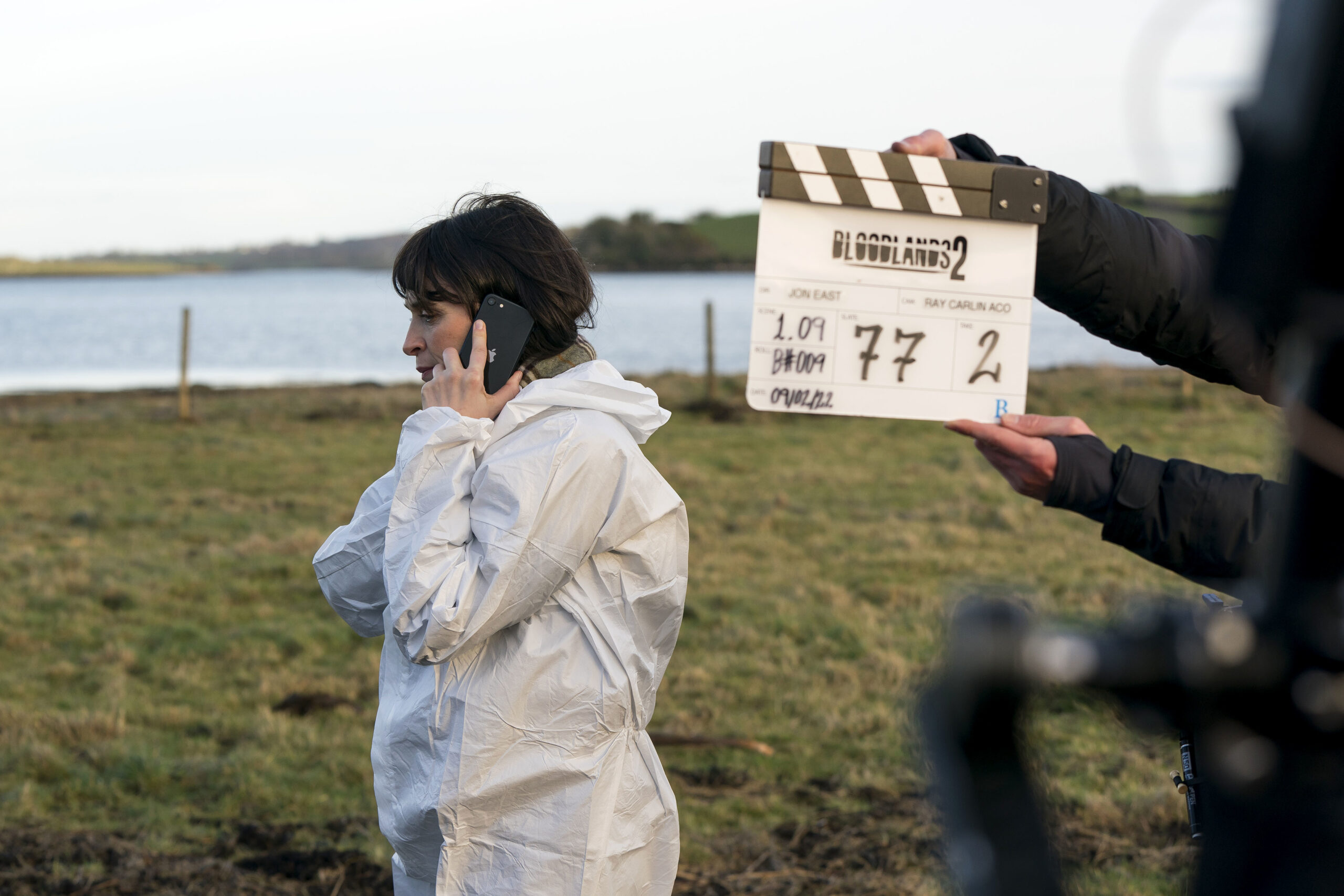 Charlene McKenna behind the scenes of bloodlands, a crew member holds up a clapper with Bloodlands written on it