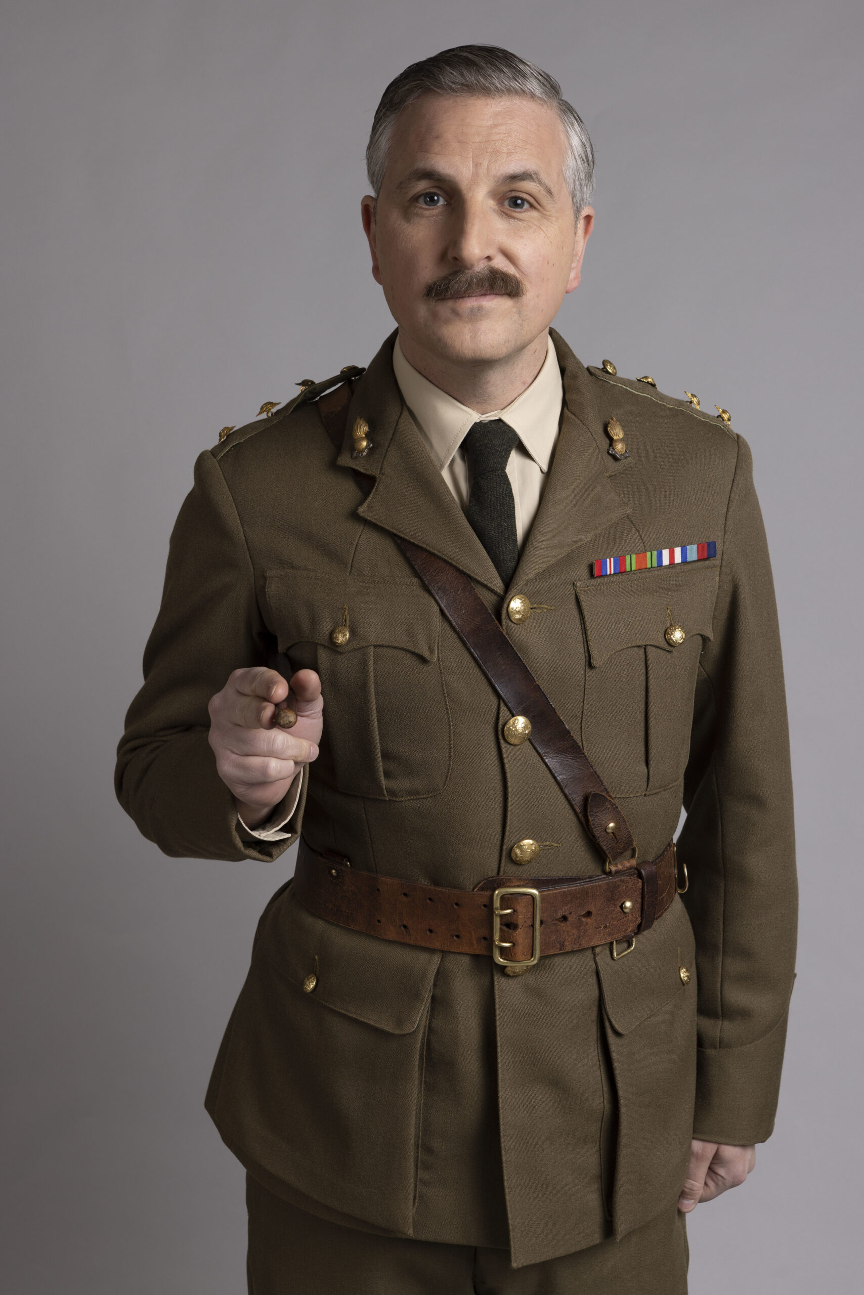 Ben Willbond as The Captain, he smiles as he points toward the camera in a World Wat Two uniform
