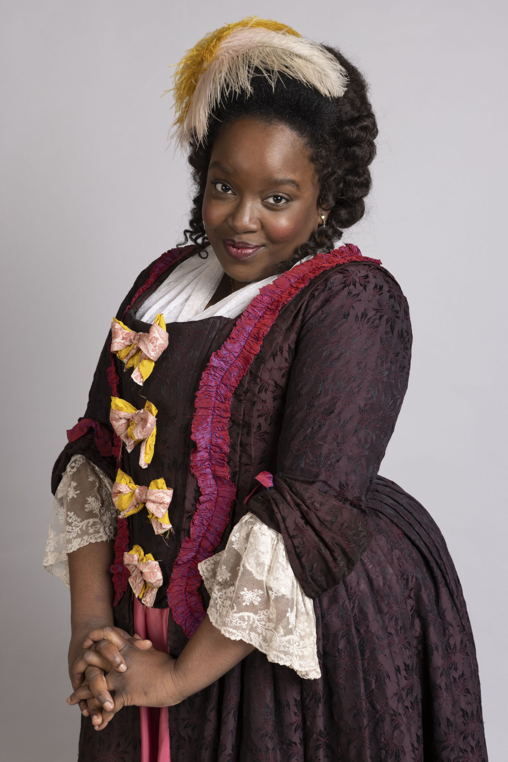 Lolly Adefope as Kitty in Ghosts, she is in Georgian clothing as she smiles towards the camera