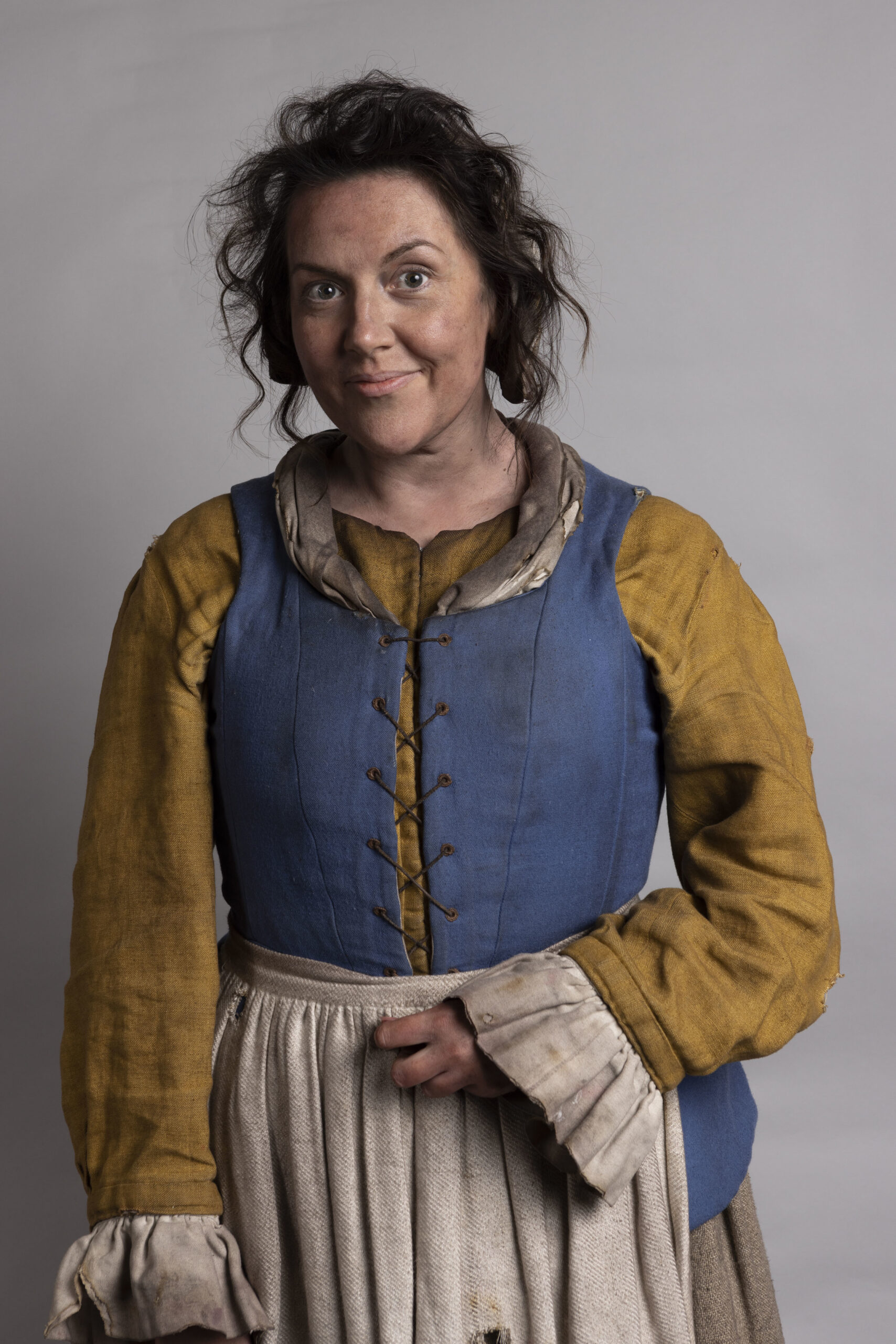 Katy Wix as Mary in Ghosts, she smiles in a burnt medieval dress