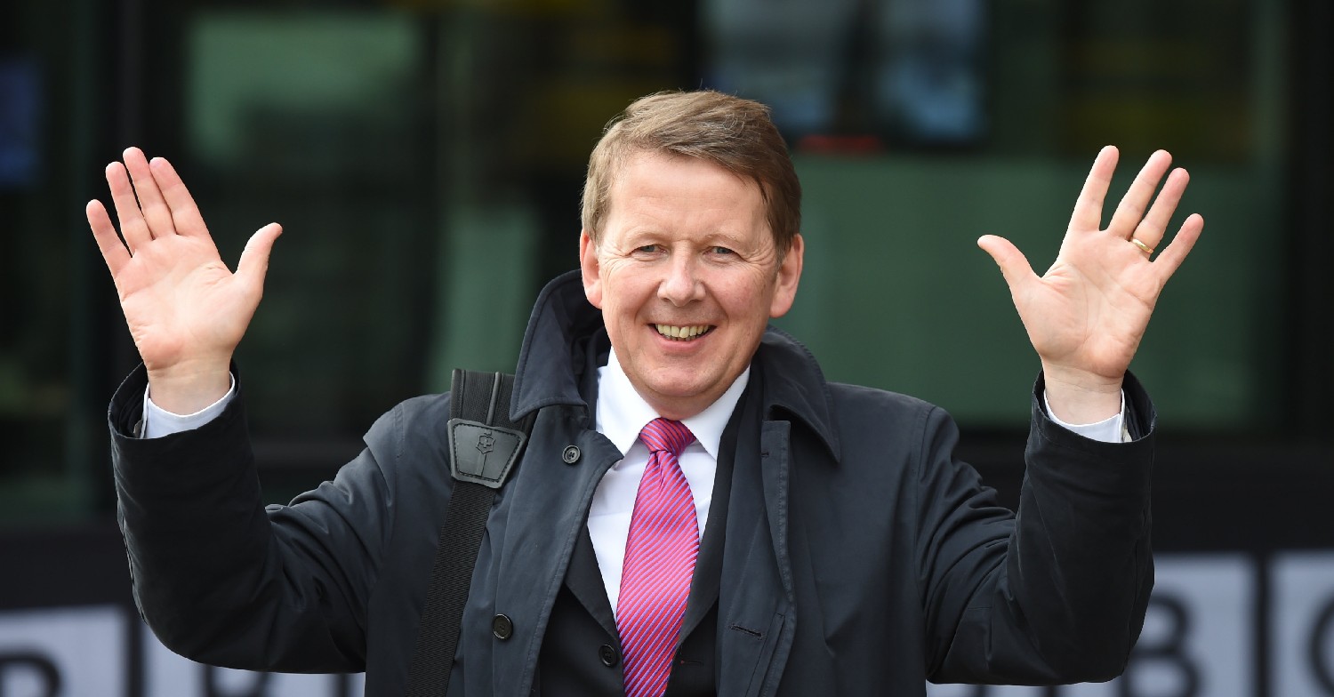 Bill Turnbull waves both hands in the air while smiling.