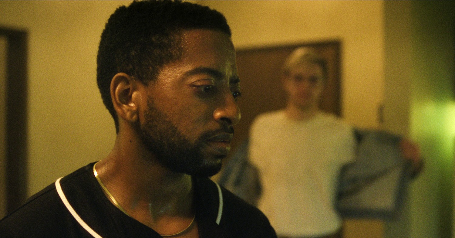 Shaun J. Brown looking to the side and Evan Peters taking off his jacket in Monster: The Jeffery Dahmer Story 