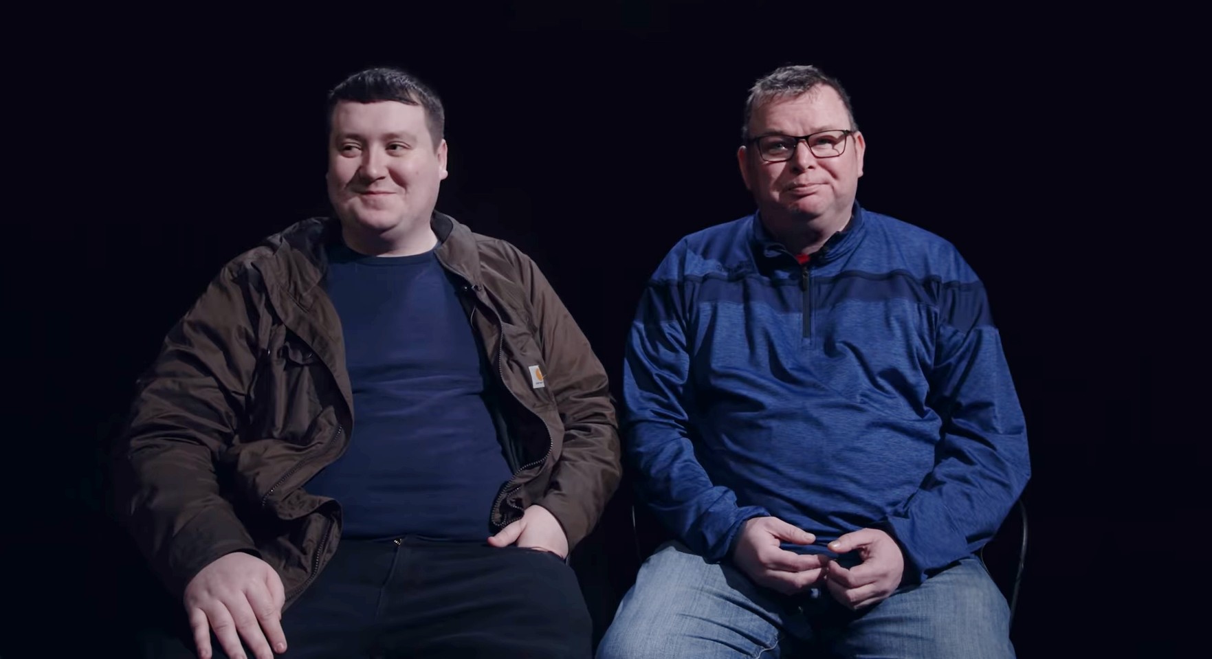 Robbie Mullen (left) and Matthew Collins (right), they sit in a dark room and smile during an interview