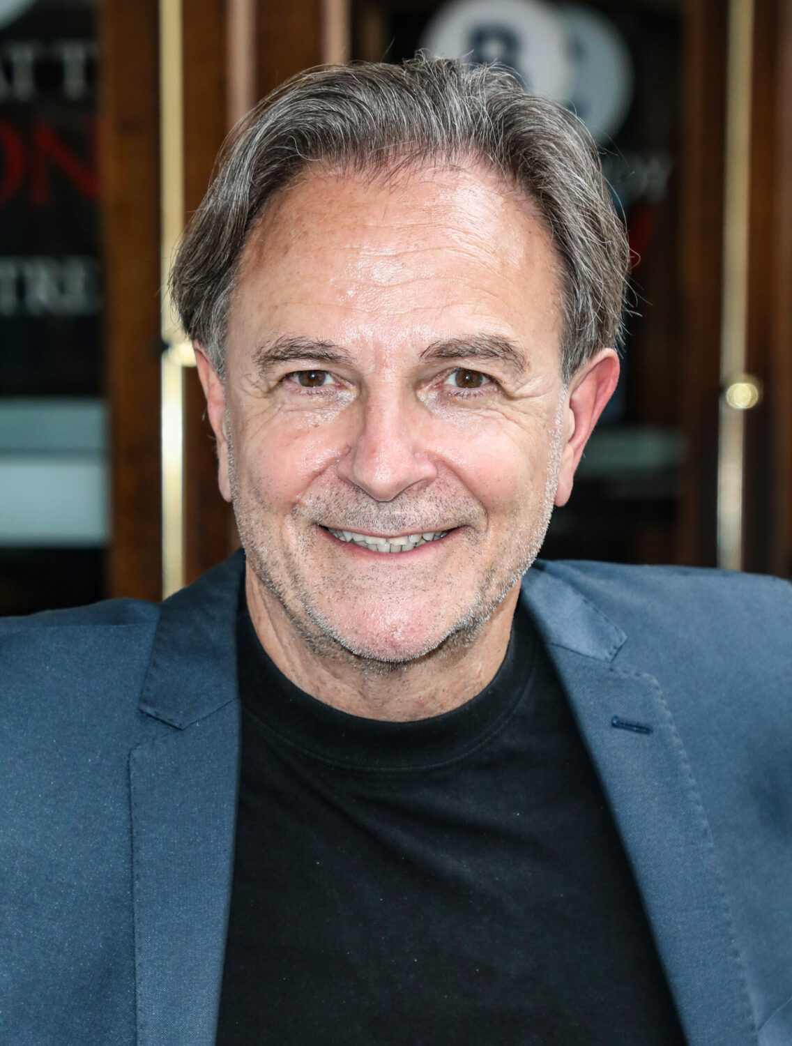 Brian Capron smiles in a blue suit and black t-shirt