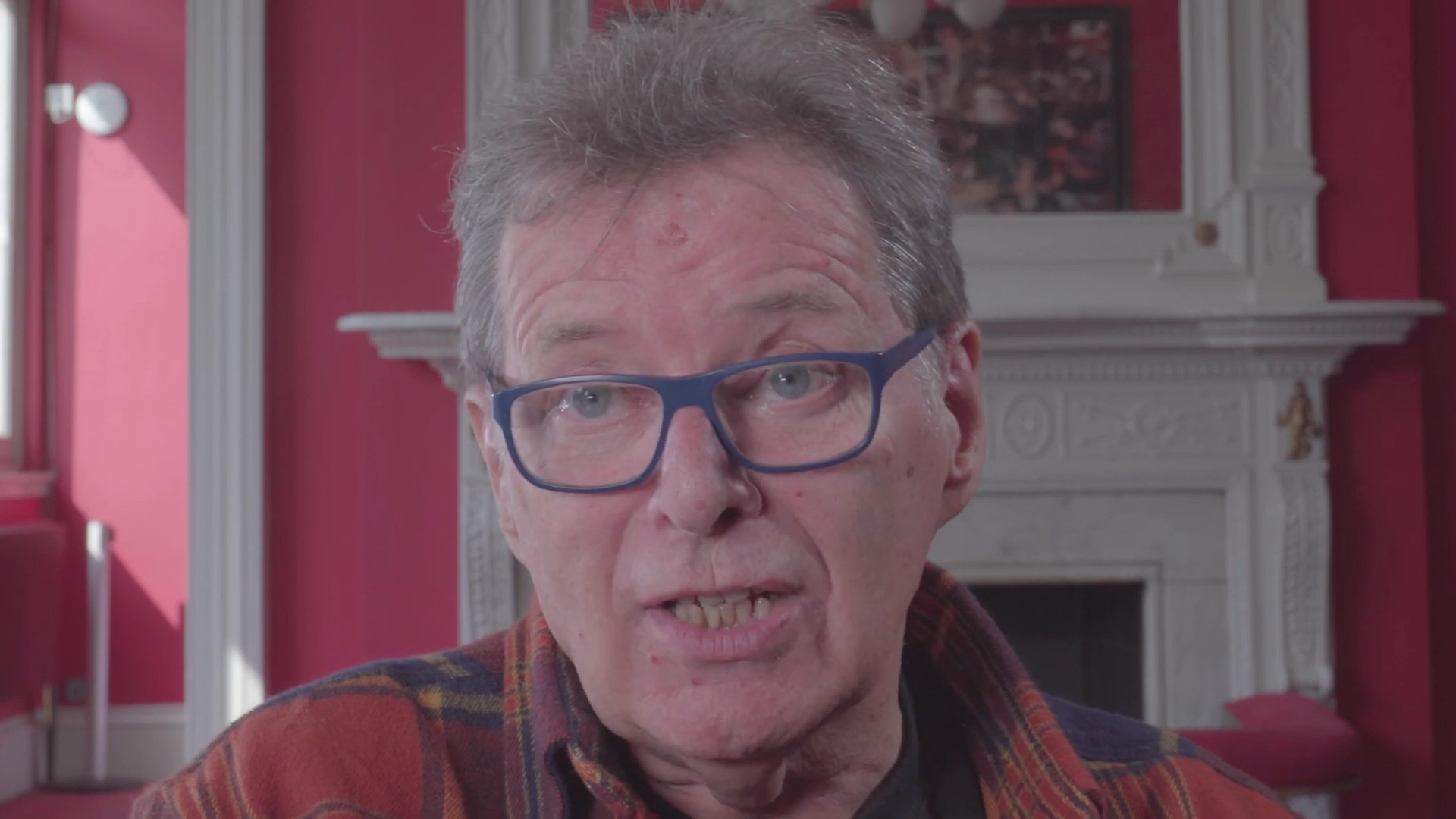 George Costigan in an interview for Lyceum Theatre, he has a red jumped on and glasses as he speaks to the camera
