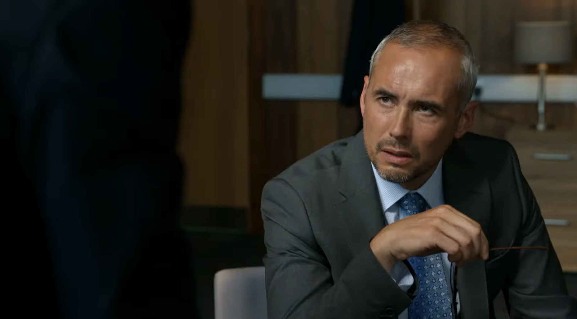 Steve John Shepherd in Karen Pirie, he looks down in a suit disappointed