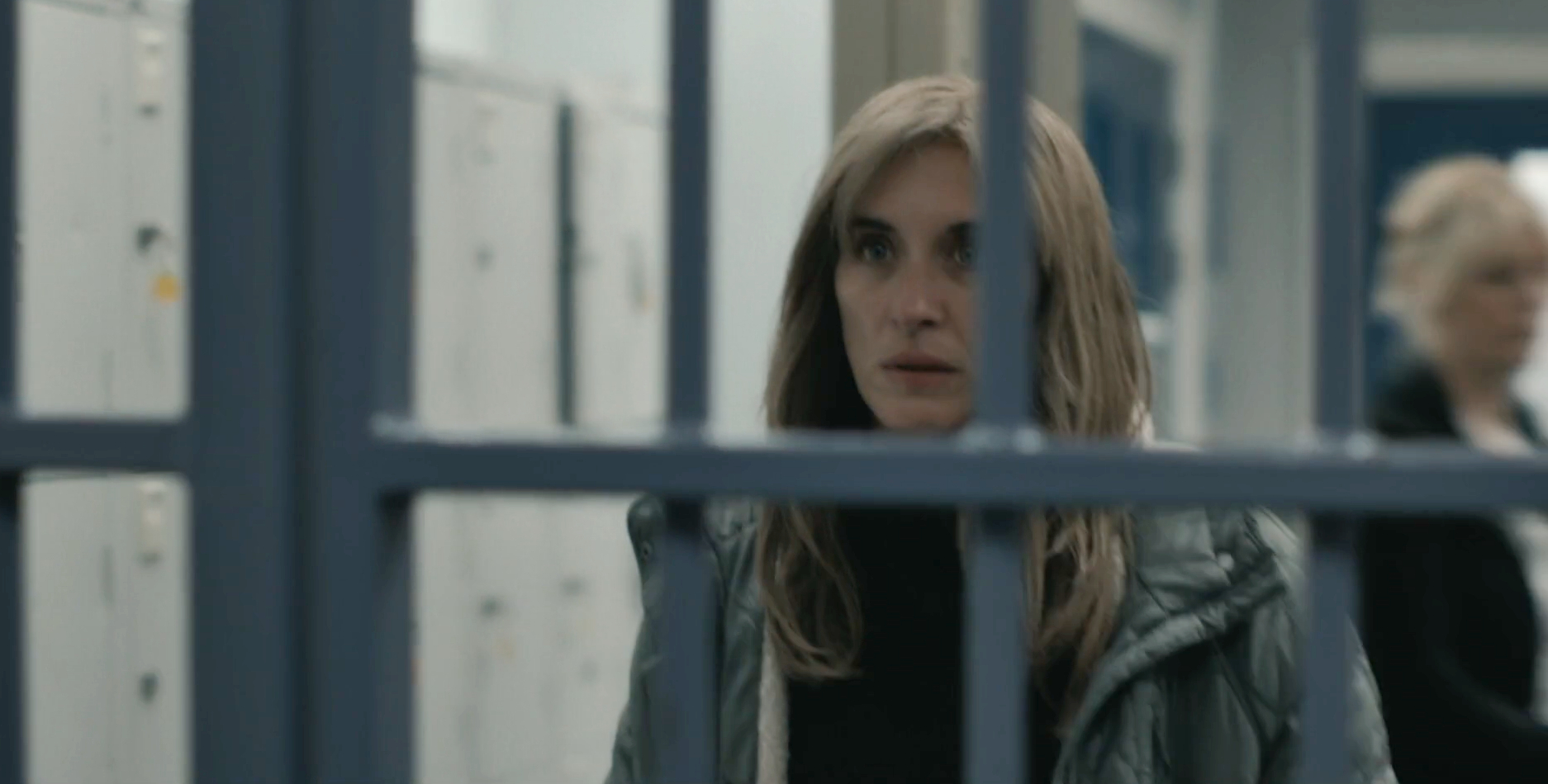 Vicky McClure as Stella Tomlinson in Without Sin, she stands in a prison, the jail cell partially blocks out the view of her